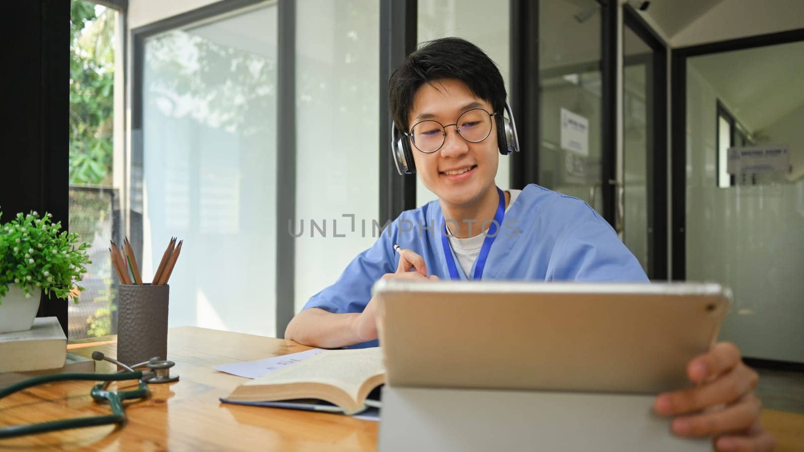 Medical student wearing headphone using digital tablet, preparing for university exams. Medical internship concept.