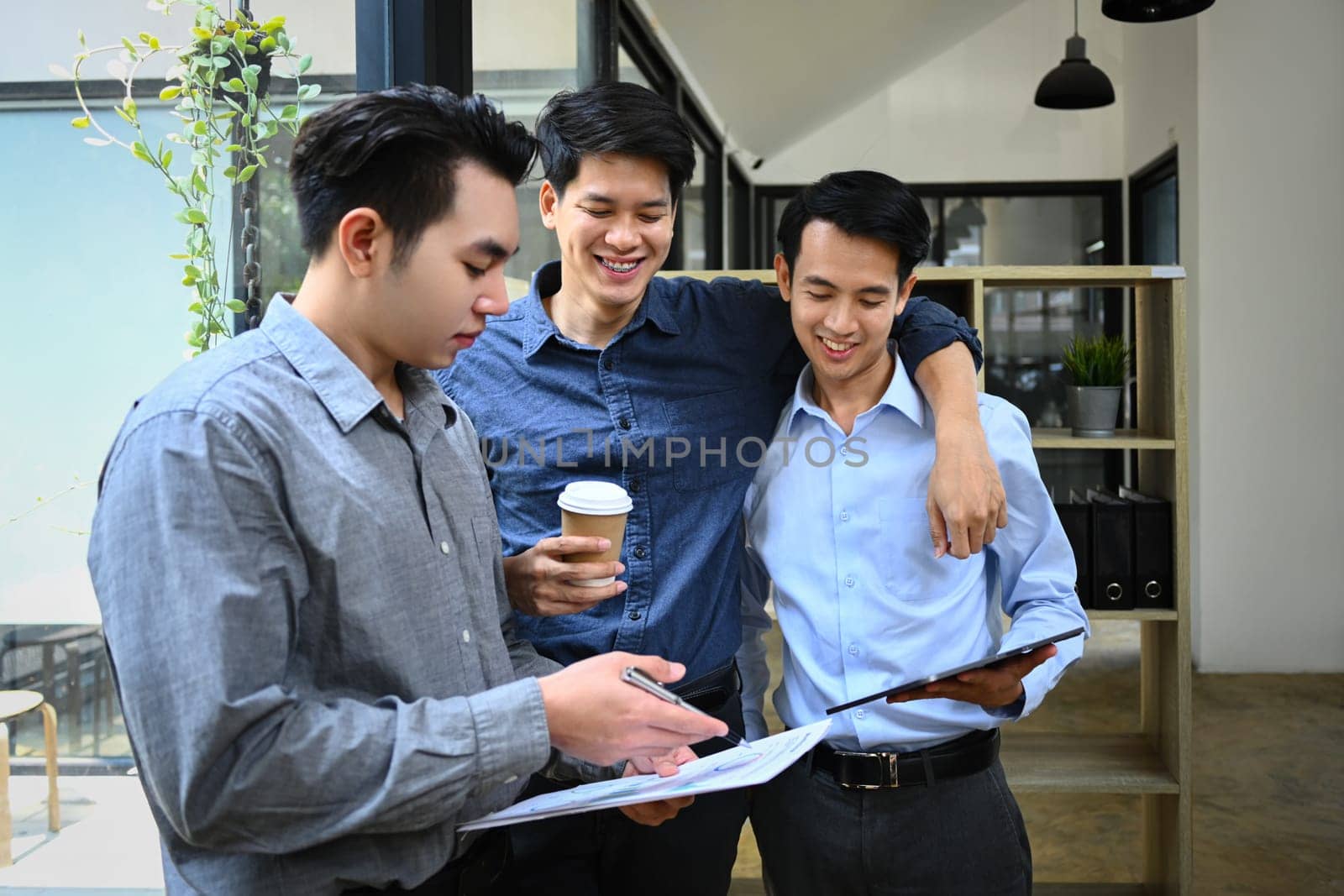 Group of coworker discussing project or sharing news during coffee break in office by prathanchorruangsak
