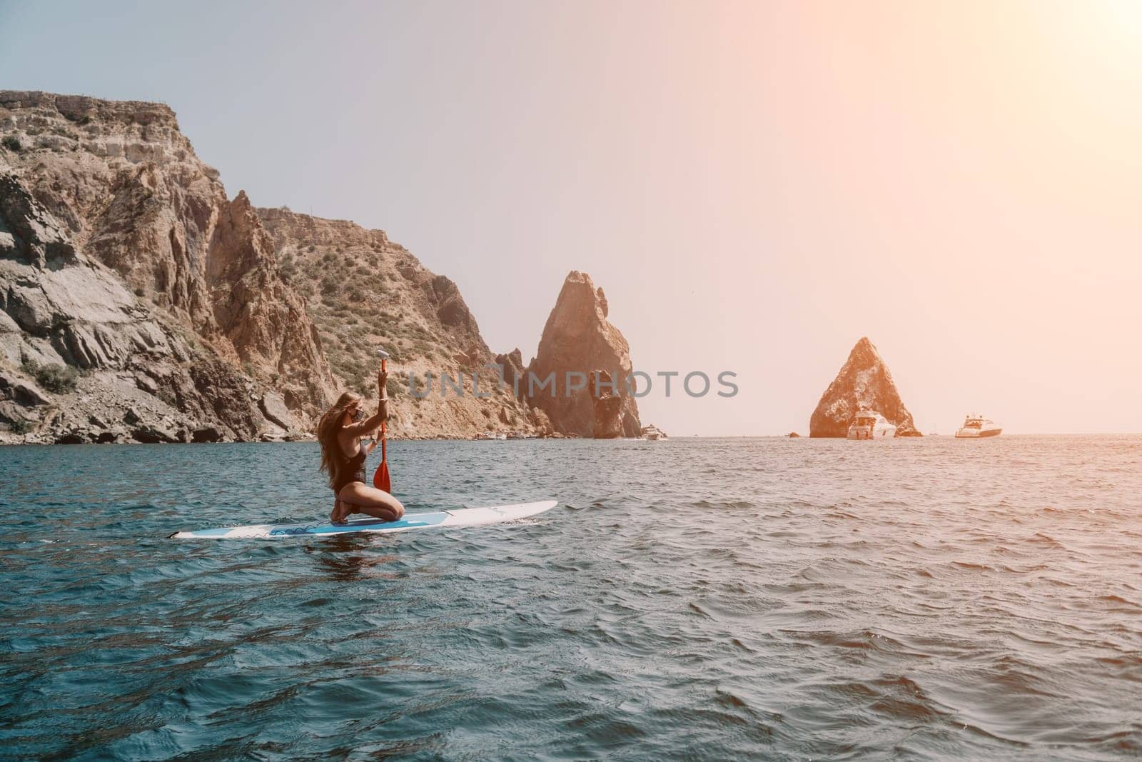 Woman sea sup. Close up portrait of happy young caucasian woman with long hair looking at camera and smiling. Cute woman portrait in bikini posing on sup board in the sea by panophotograph