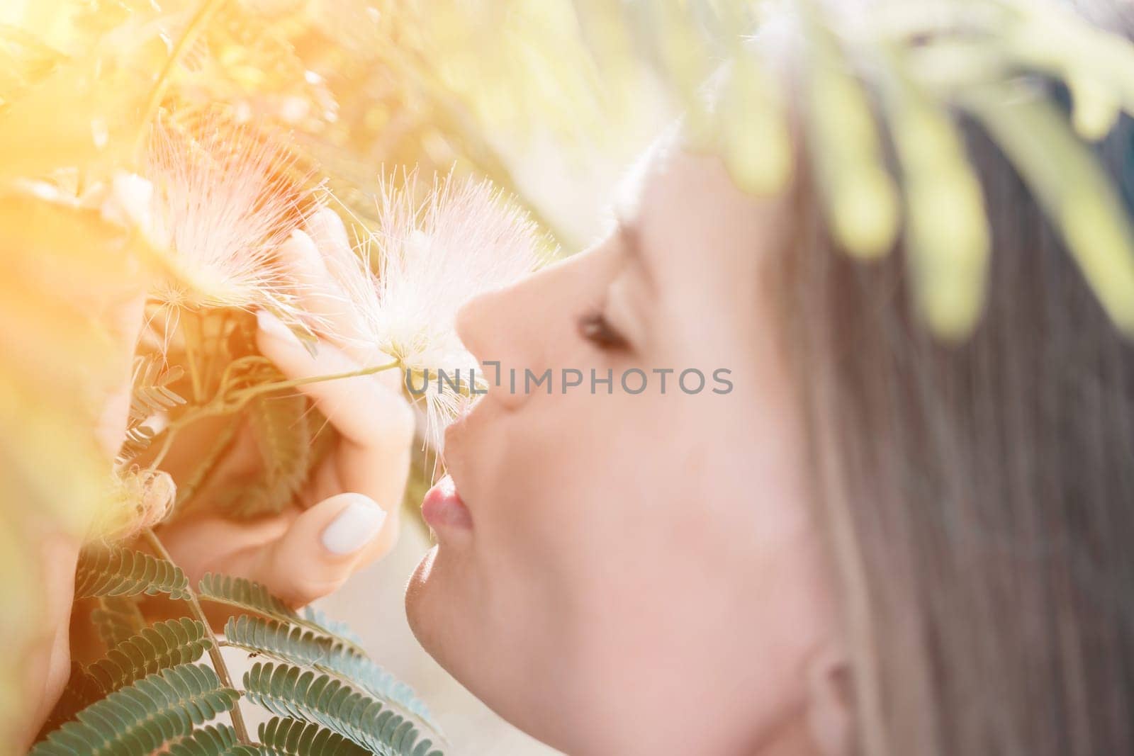Beauty portrait of young woman closeup. Young girl smelling Chinese acacia pink blossoming flowers. Portrait of young woman in blooming spring, summer garden. Romantic vibe. Female and nature.