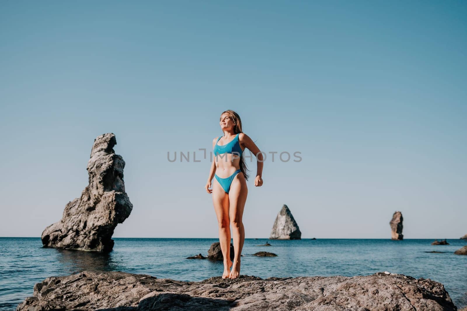 Middle aged well looking woman with black hair doing Pilates with the ring on the yoga mat near the sea on the pebble beach. Female fitness yoga concept. Healthy lifestyle, harmony and meditation.