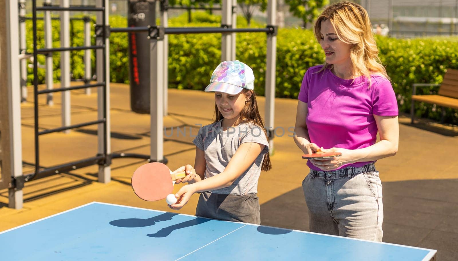 Happy Mother and Daughter Learning to Play Ping Pong Sport Cheerful family playing leisure sports enjoying table tennis.