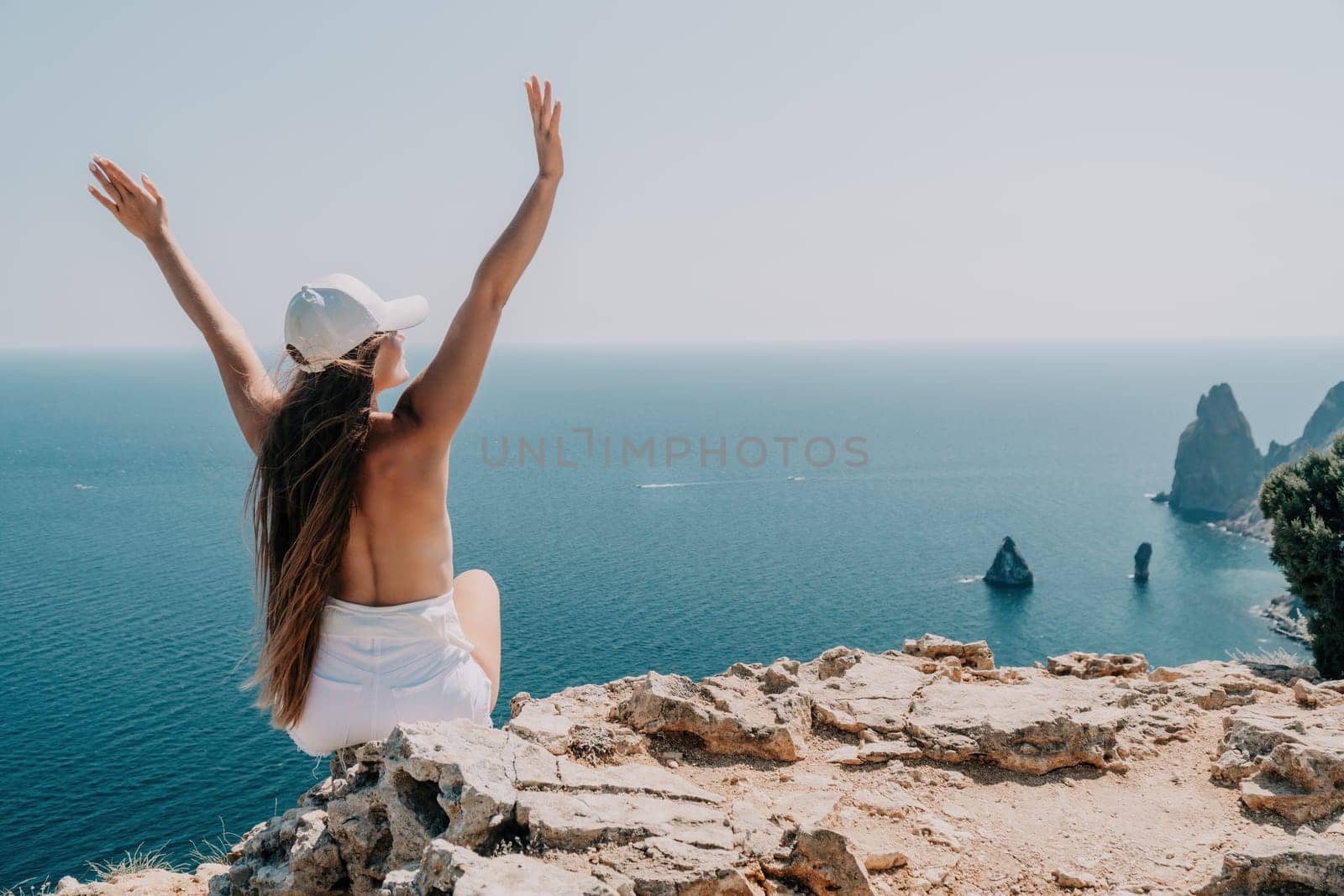 Woman travel sea. Young Happy woman in a long red dress posing on a beach near the sea on background of volcanic rocks, like in Iceland, sharing travel adventure journey