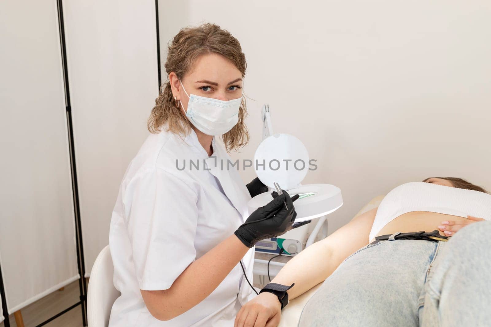 Cosmetologist Doing Hair Removal Procedure With Electrolysis On Hand Of White Young Patient, Electroepilation In Beauty Salon. Horizontal Plane. Authentic High quality photo. by netatsi