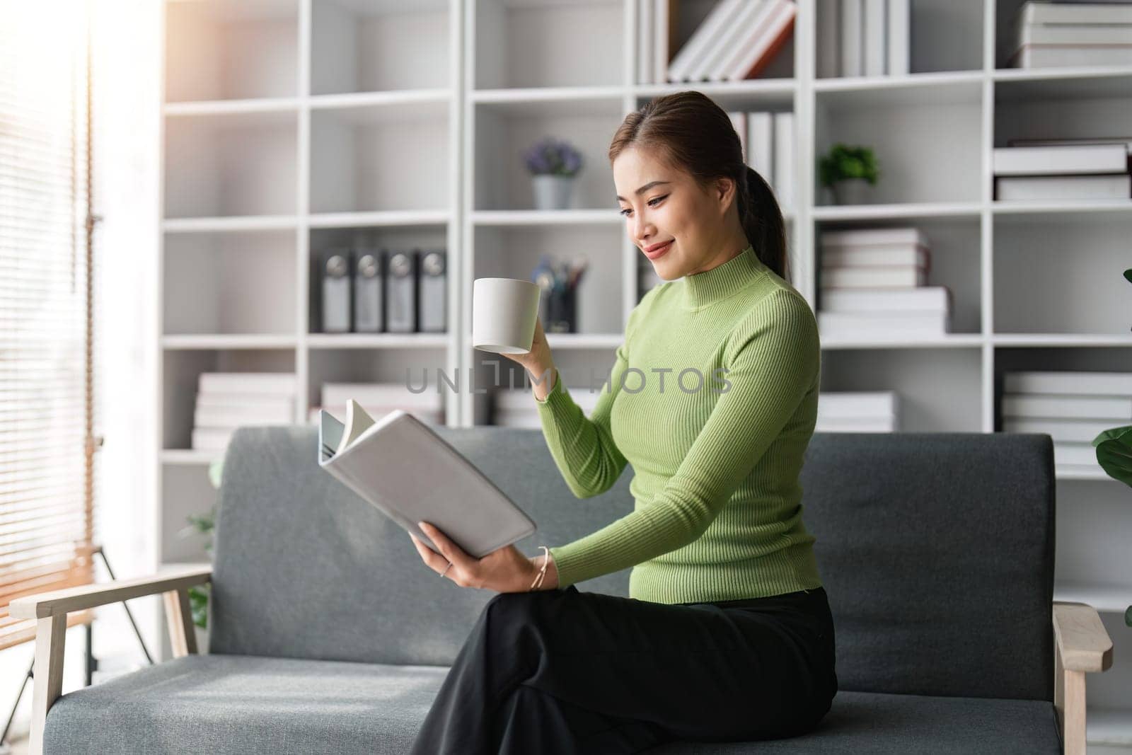 Young woman relaxing and drinking cup of hot coffee or tea woman checking document and working.