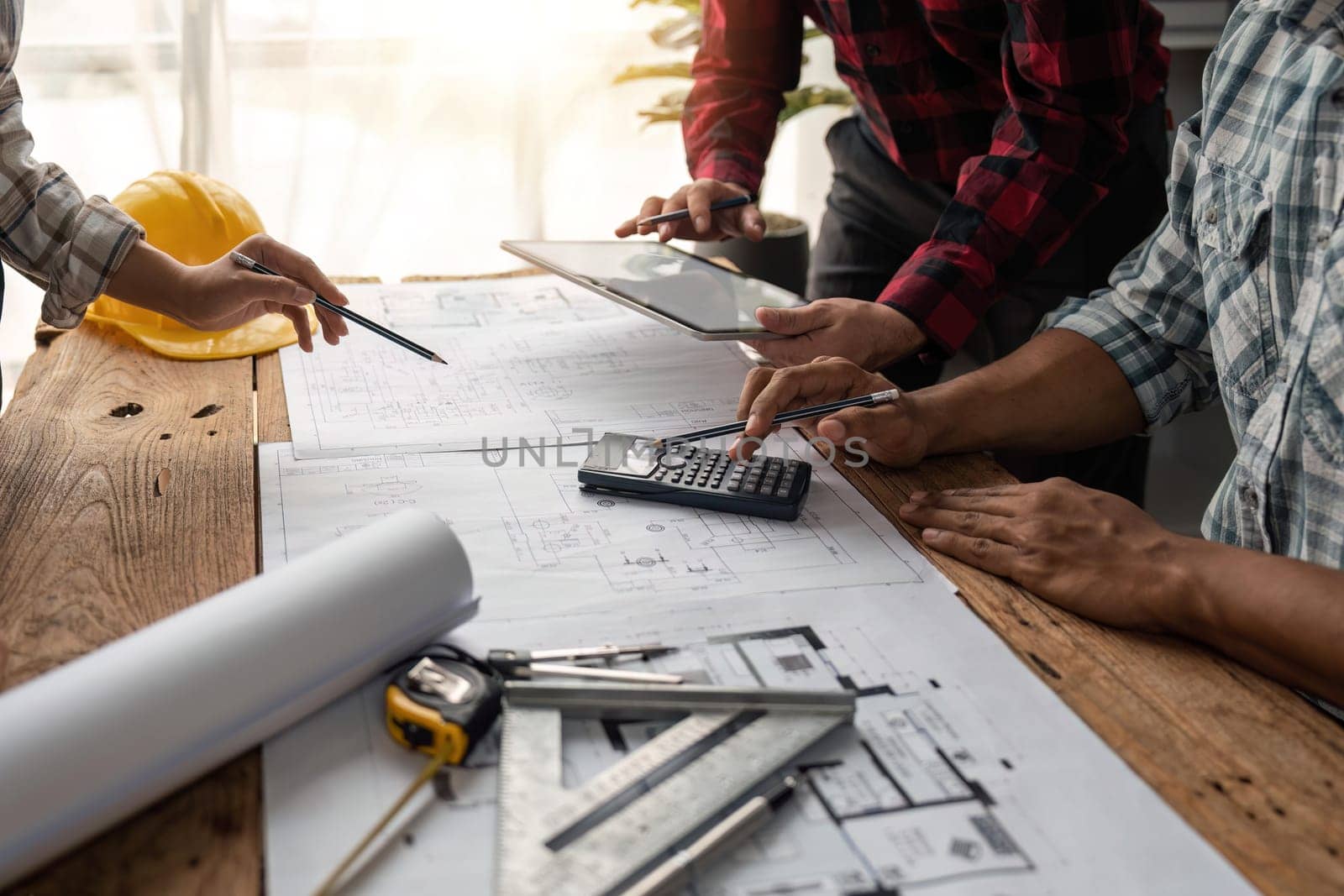 team engineer checks construction blueprints on new project with engineering tools at desk in office.