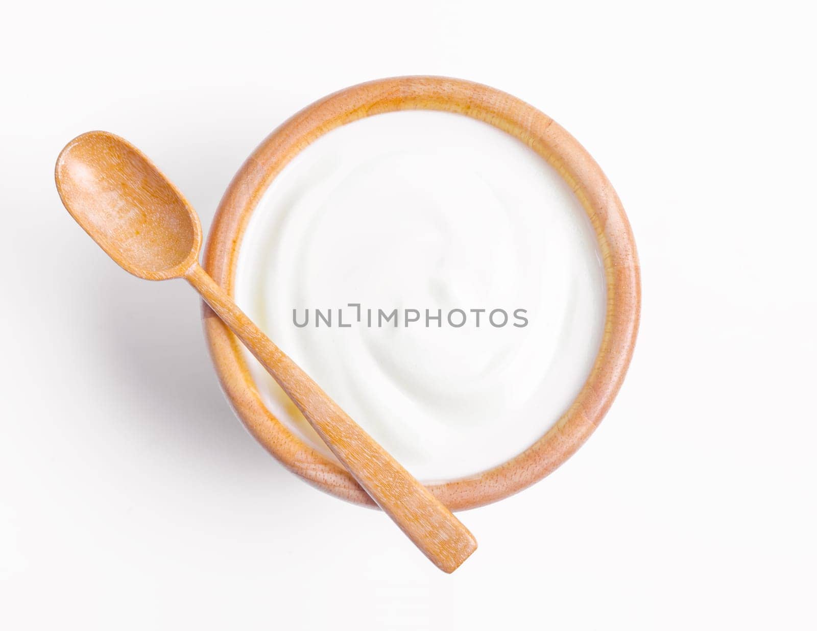 Fresh greek yogurt in wooden bowl with wooden spoon on white background. Healthy breakfast.