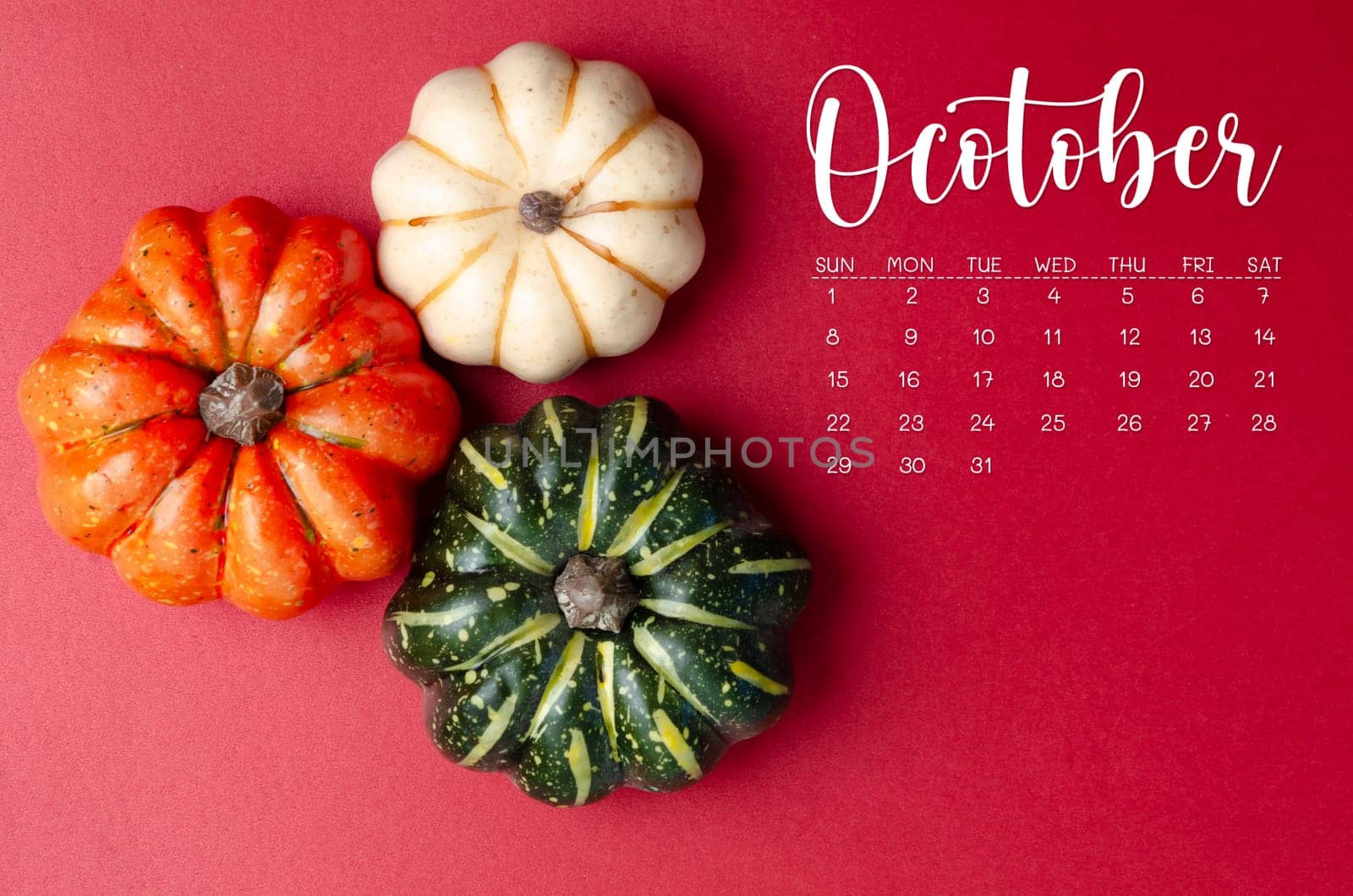 October 2023 Calendar and pumpkins on red cardboard background.