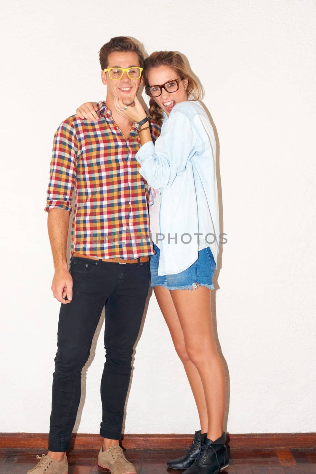 Goofy portrait of hipster couple, funny face with glasses and gen z fashion with university youth culture. Happiness, woman and man in crazy picture on fun college date with white wall background. by YuriArcurs
