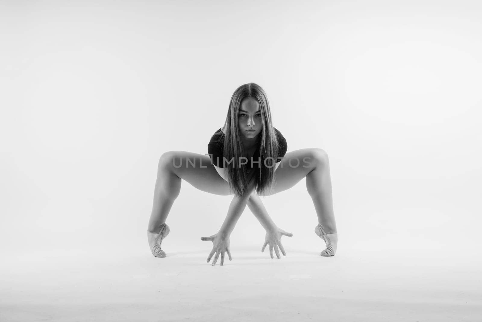 Flexible girl, rhythmic gymnastics artist jumping on white dark background. Grace in motion, action. by Zelenin