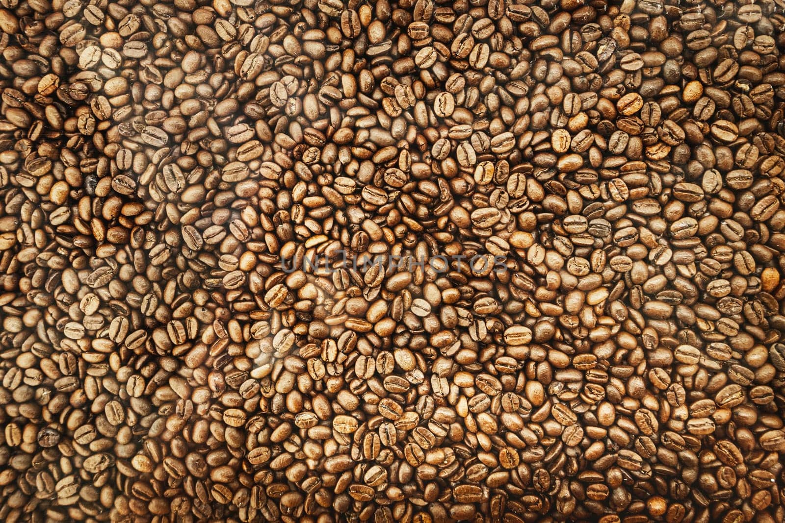 Background of brown roasted coffee beans, top view texture.