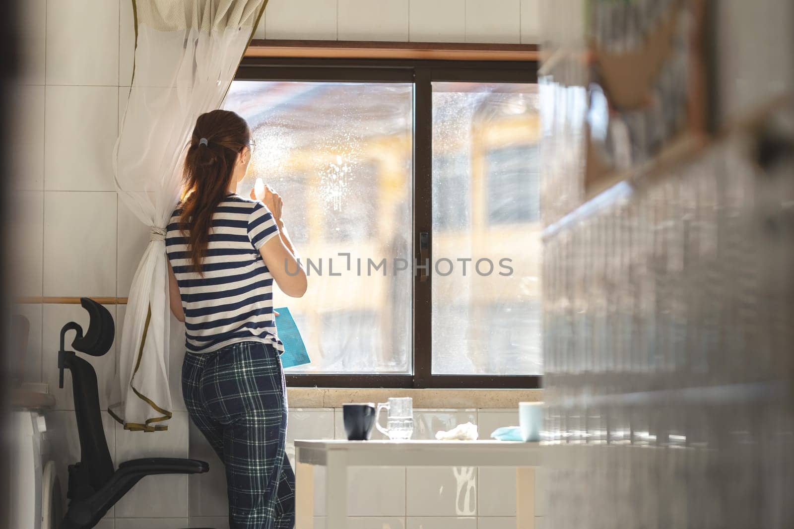 A woman housewife spraying window cleaner at the glass. Mid shot