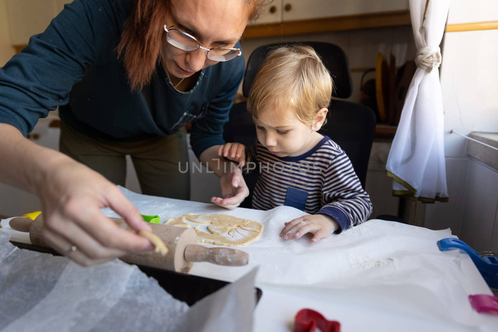 A woman with her little son making cookies on the kitchen. Mid shot