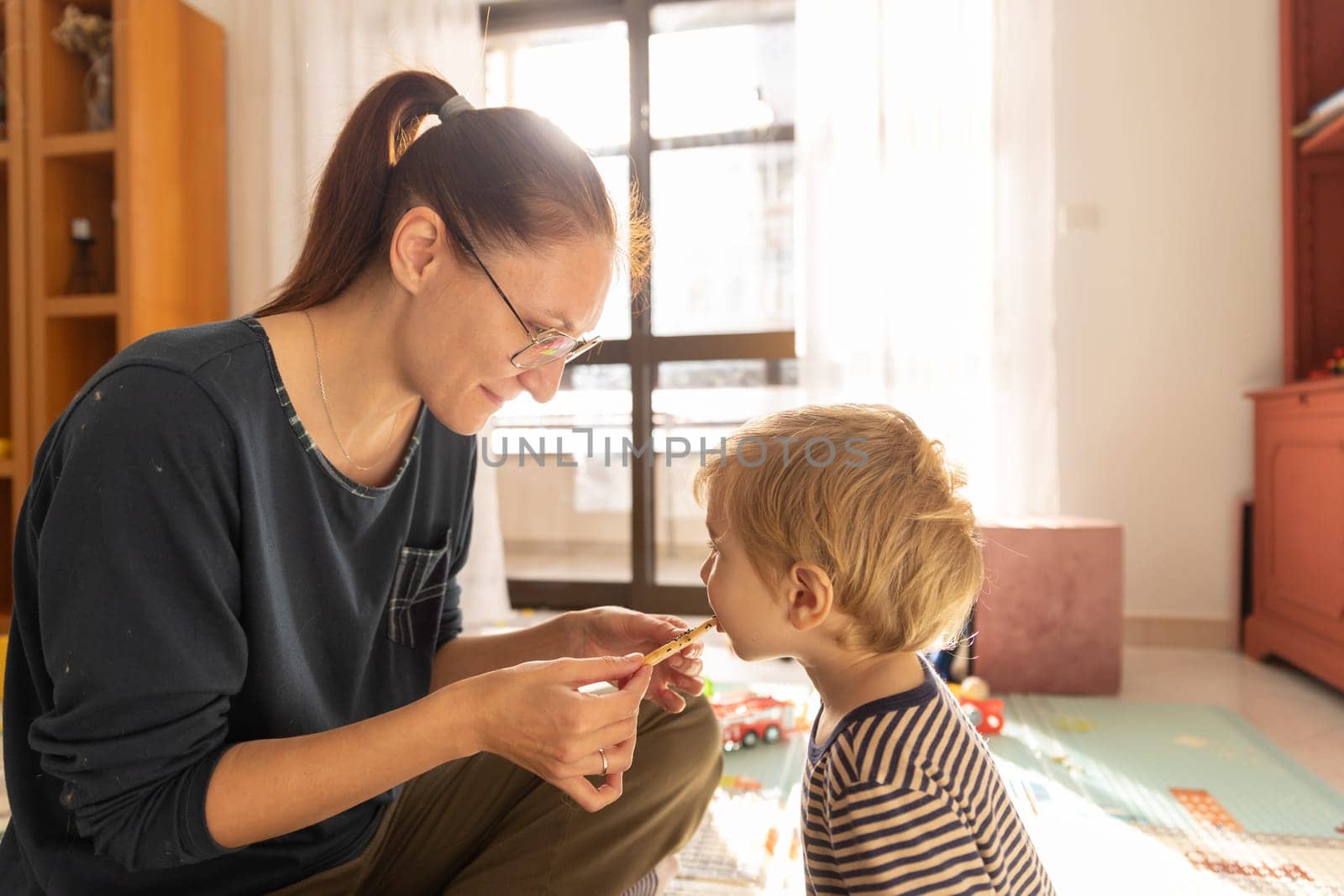 Mom feeds her son freshly made cookies in the playroom. Mid shot