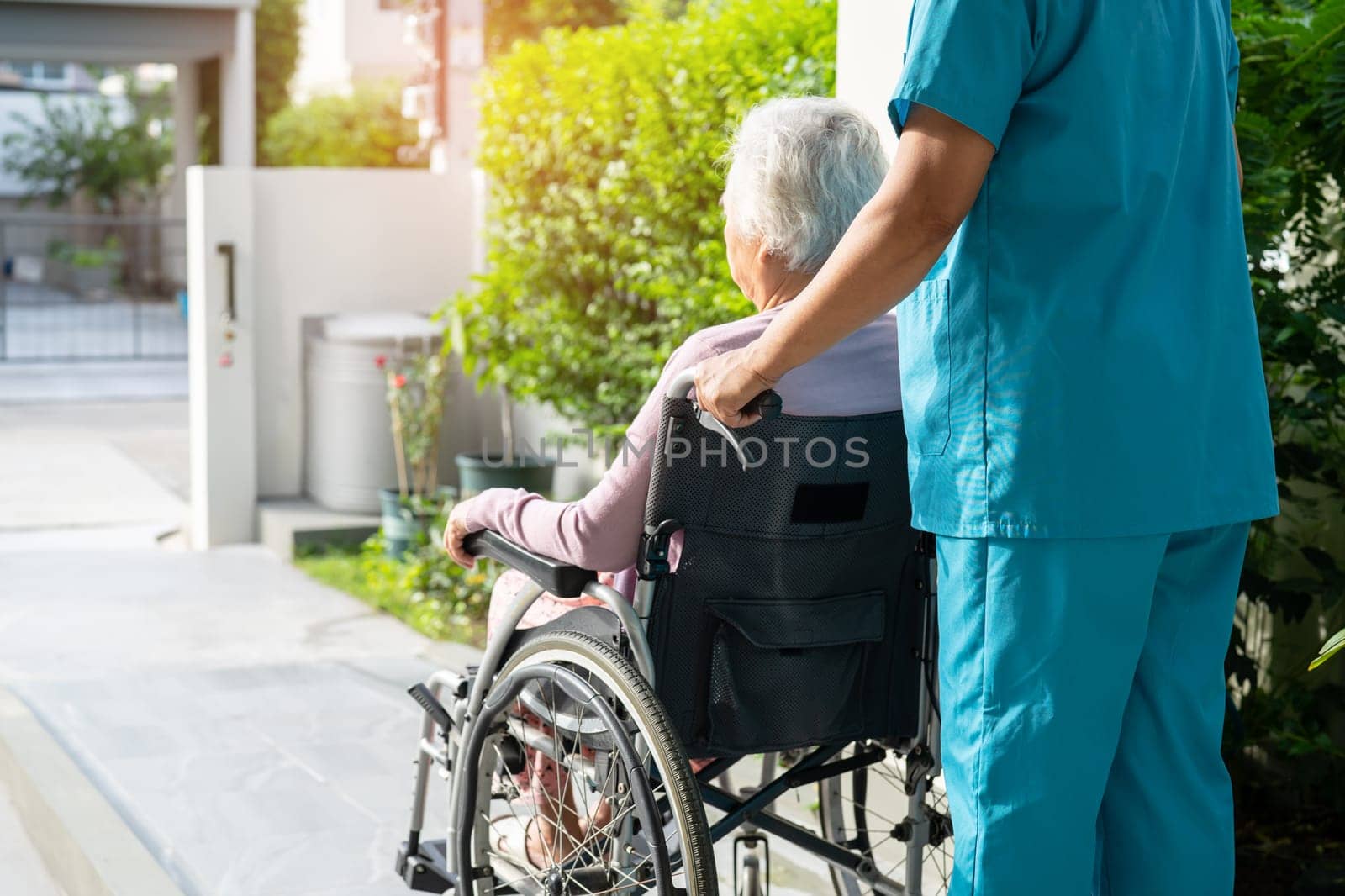 Caregiver help and care Asian senior or elderly old lady woman patient sitting on wheelchair to ramp in nursing hospital, healthy strong medical concept. by pamai