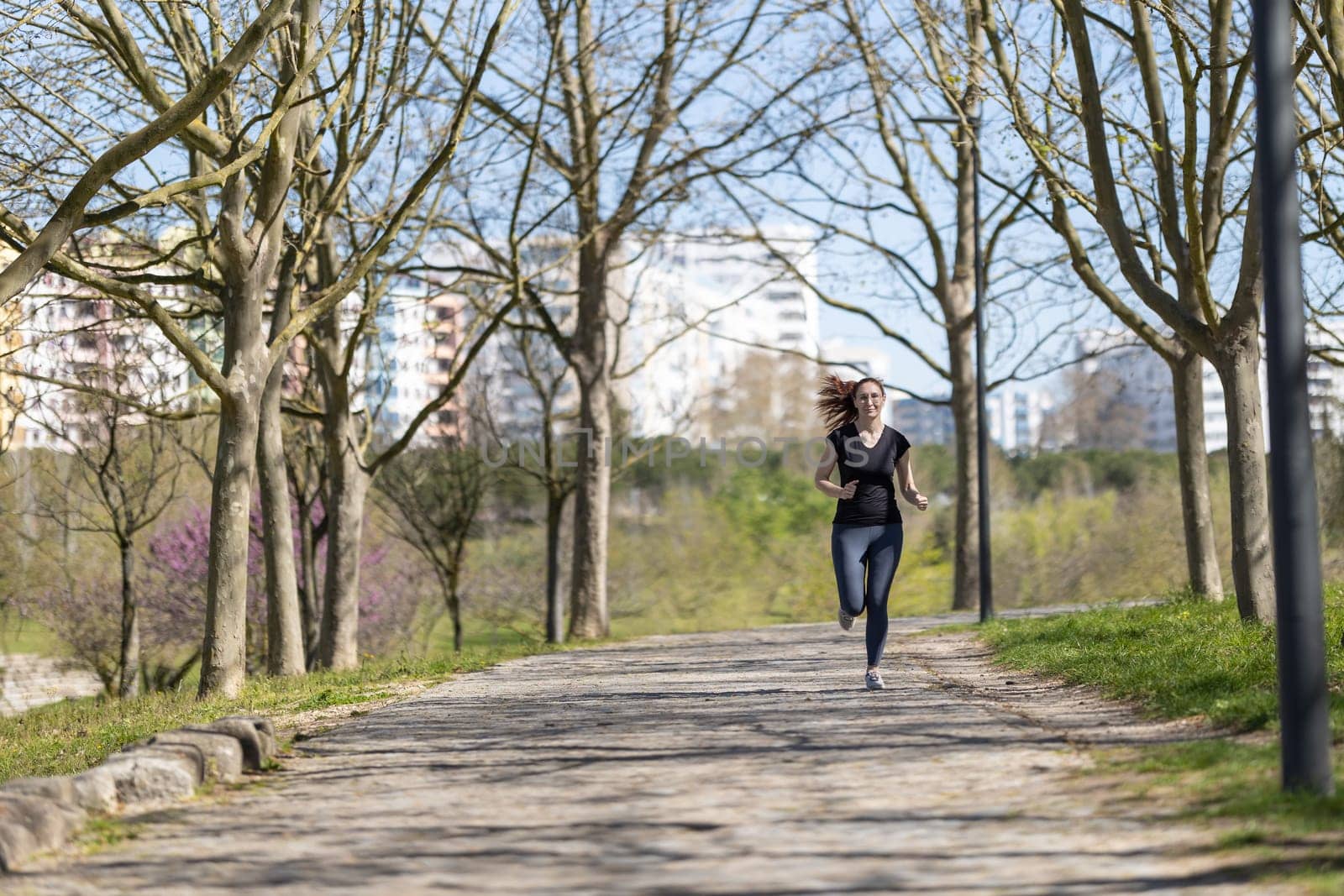 Adult sportive woman jogging in the park. Mid shot