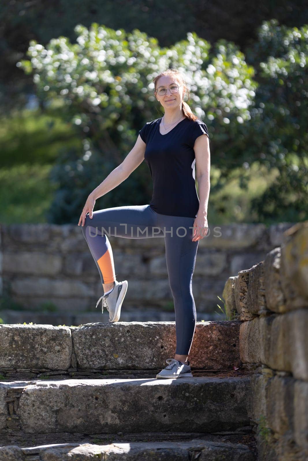 Adult smiling woman in sports clothes in the park. Vertical shot
