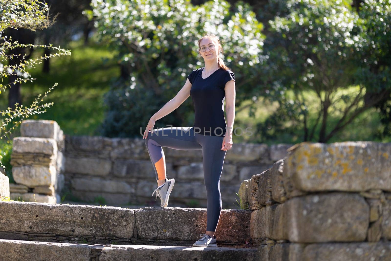 Adult smiling woman in sports clothes in the park. Mid shot