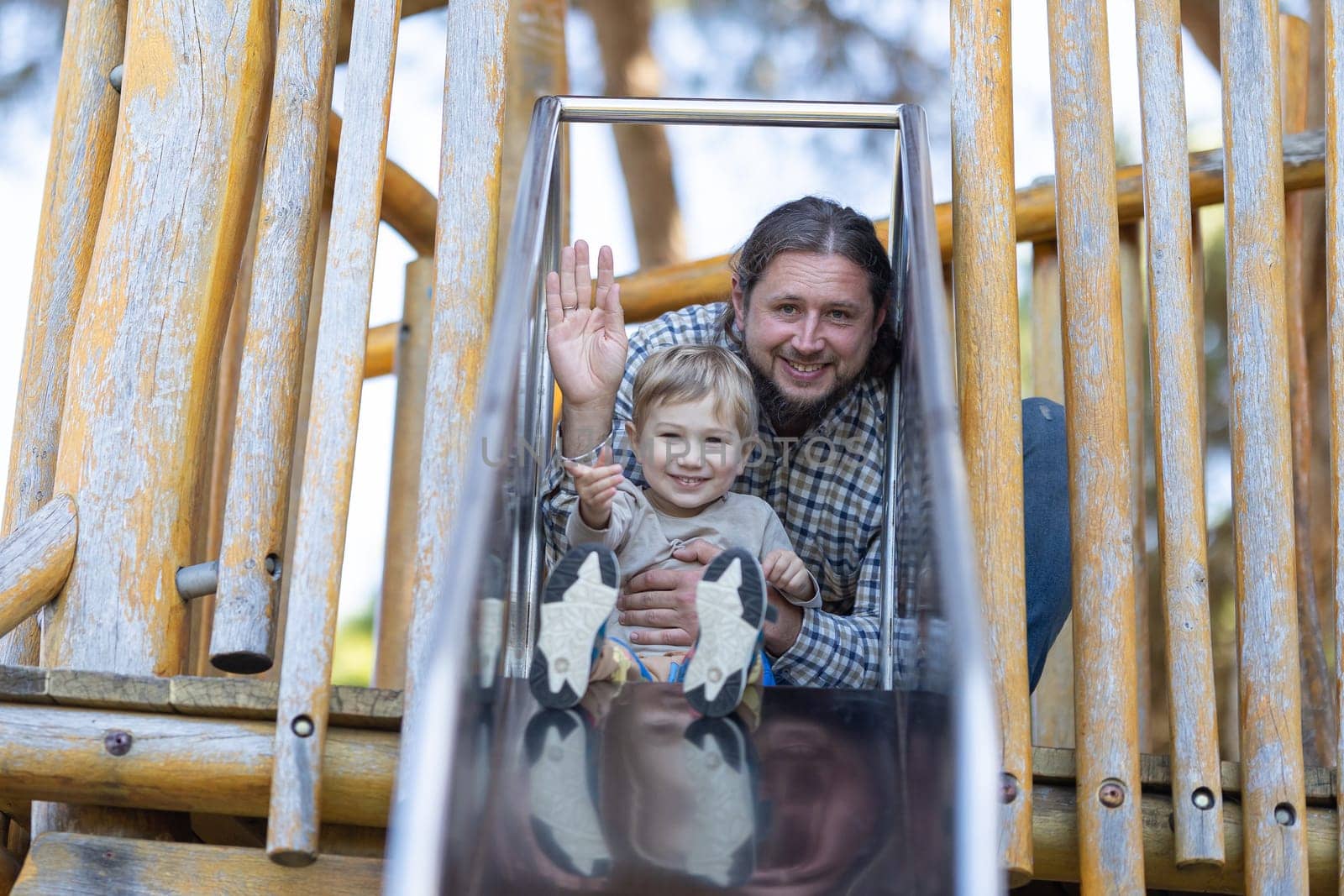 Cute little boy and his father on the playground. Mid shot