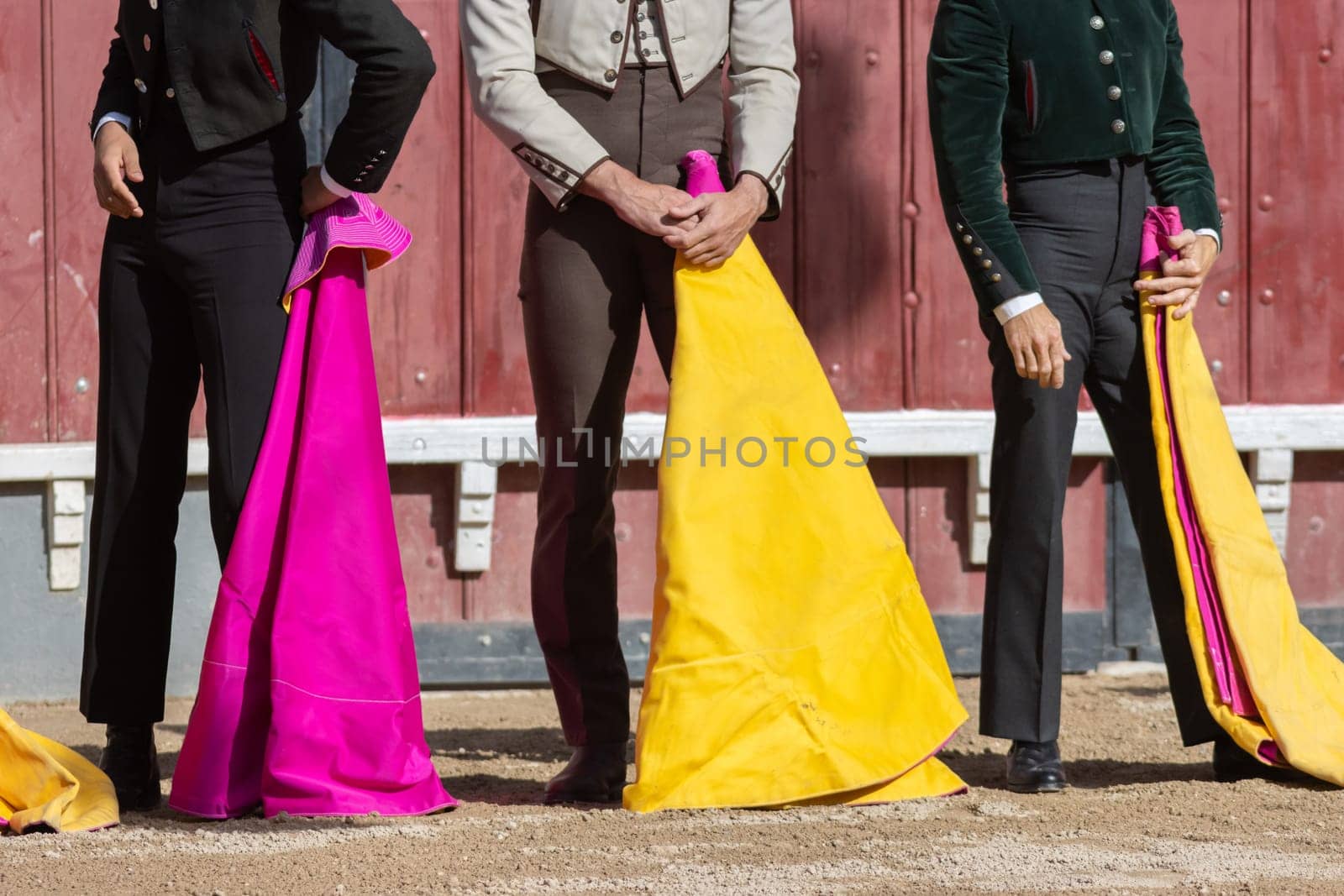 Tourada - bullfighters standing on the arena holding bright tags by Studia72