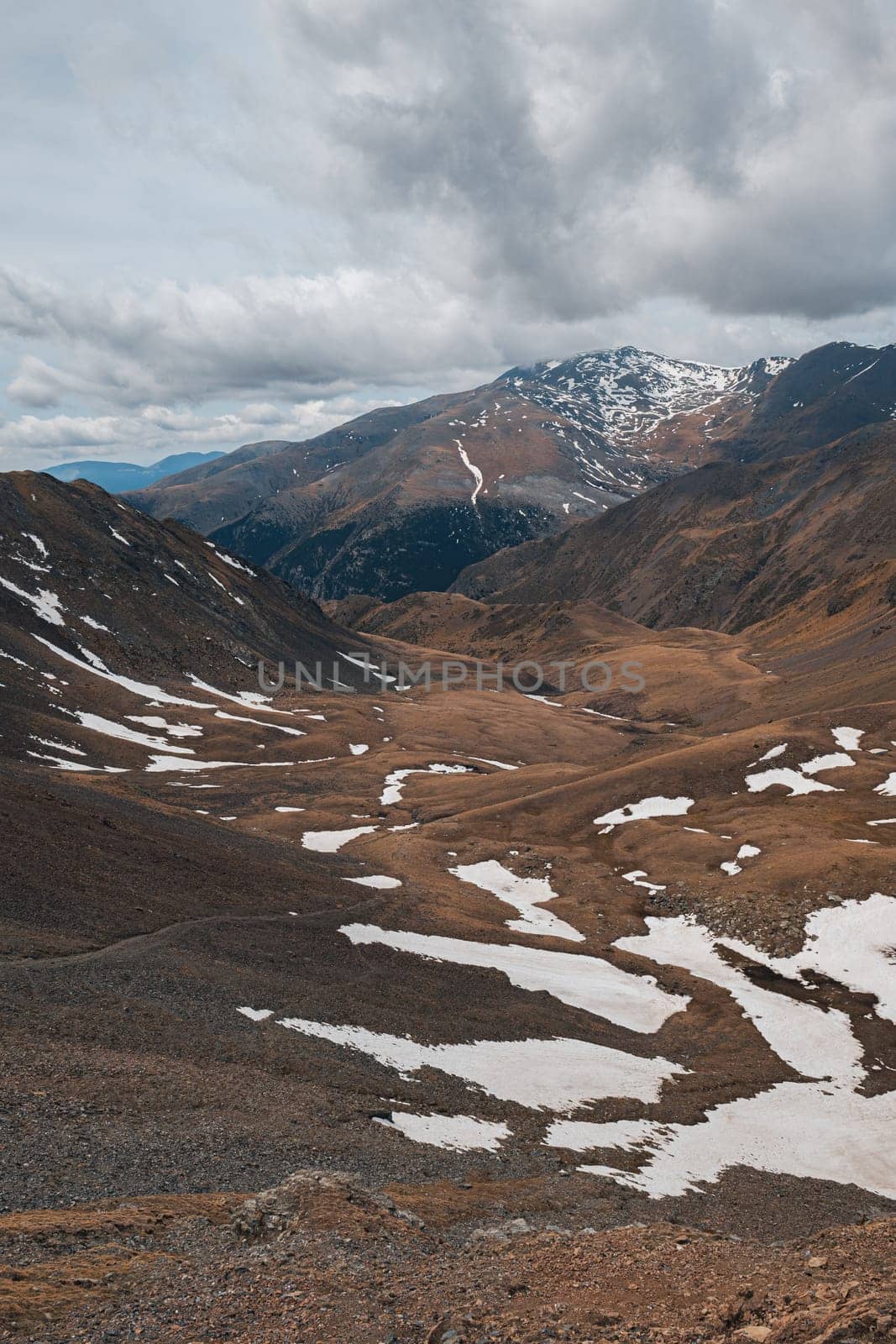 Vertical shot of a picturesque view of a snow-covered valley among the Pyrenean slopes on a cloudy autumn day. The concept of the harsh mountainous Spanish nature.