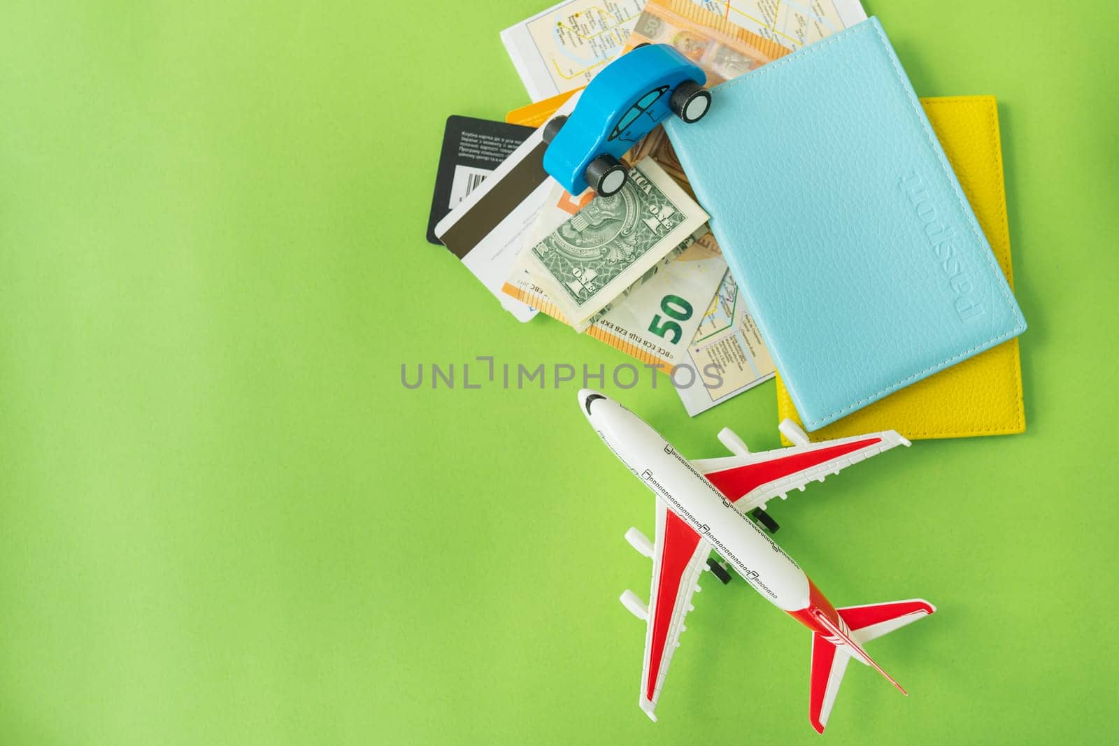 Composition from a city map with a bank card, euro, dollar banknotes, passports and a toy plane on a green background. Travel and vacation concept