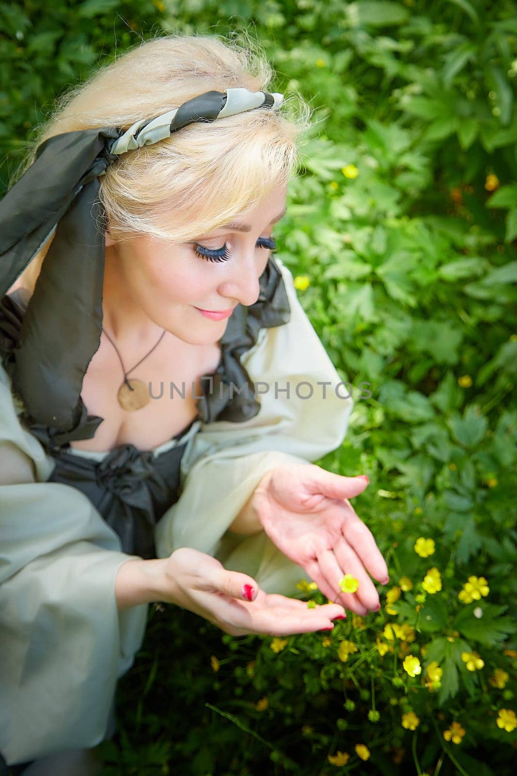 Adult mature woman 40-60 in a green long fairy dress in forest. Photo shoot in style of dryad and queen of nature. Fairy in beautiful green summer forest. Concept of caring for nature