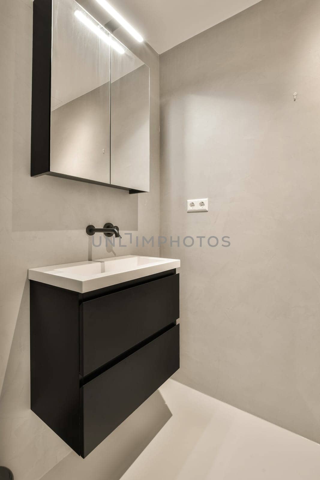 a modern bathroom with black cabinets and white countertops on the wall above the sink is an illuminated mirror