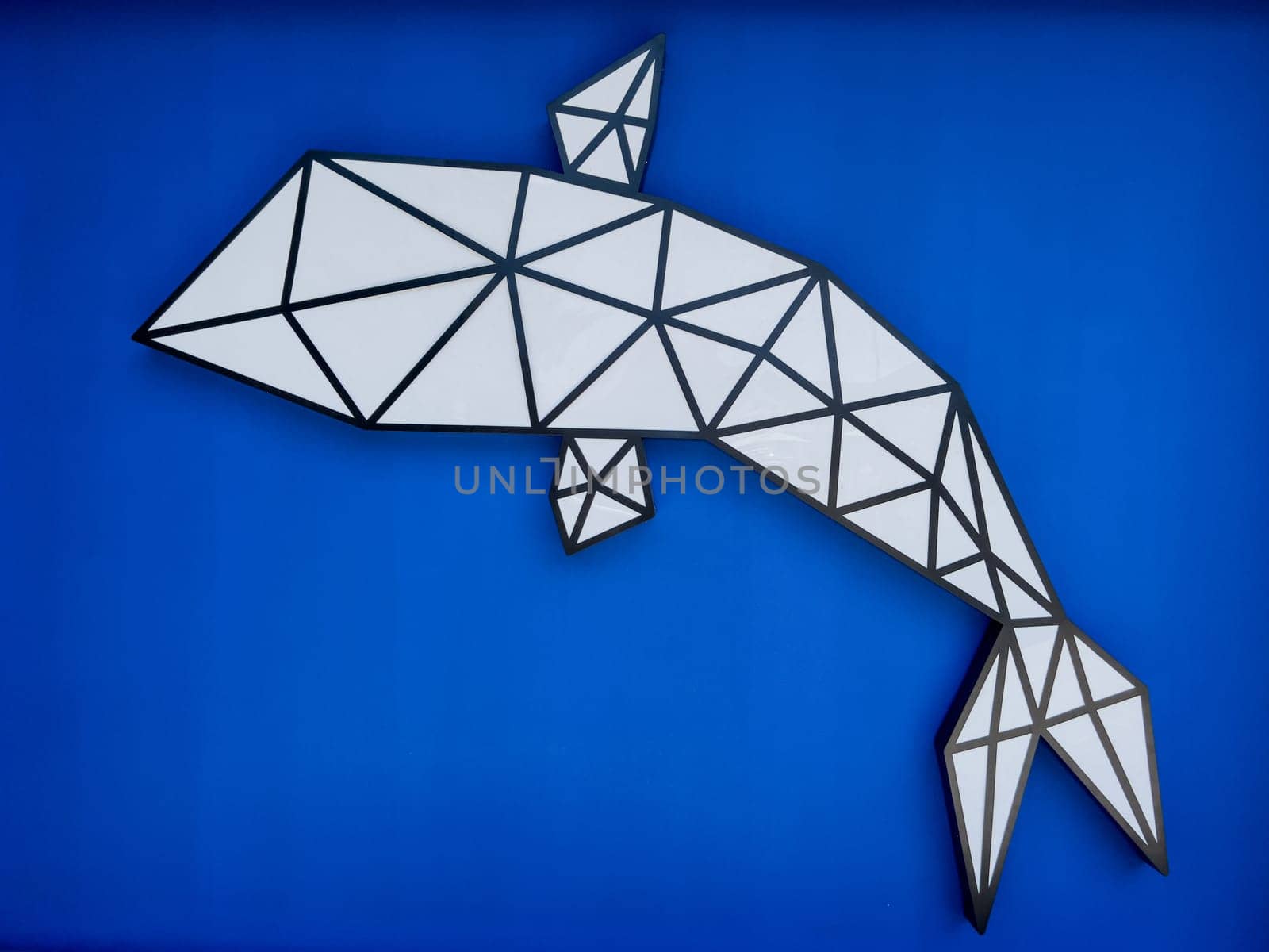 Decorative panel in the form of a whale on a blue wall. High quality photo