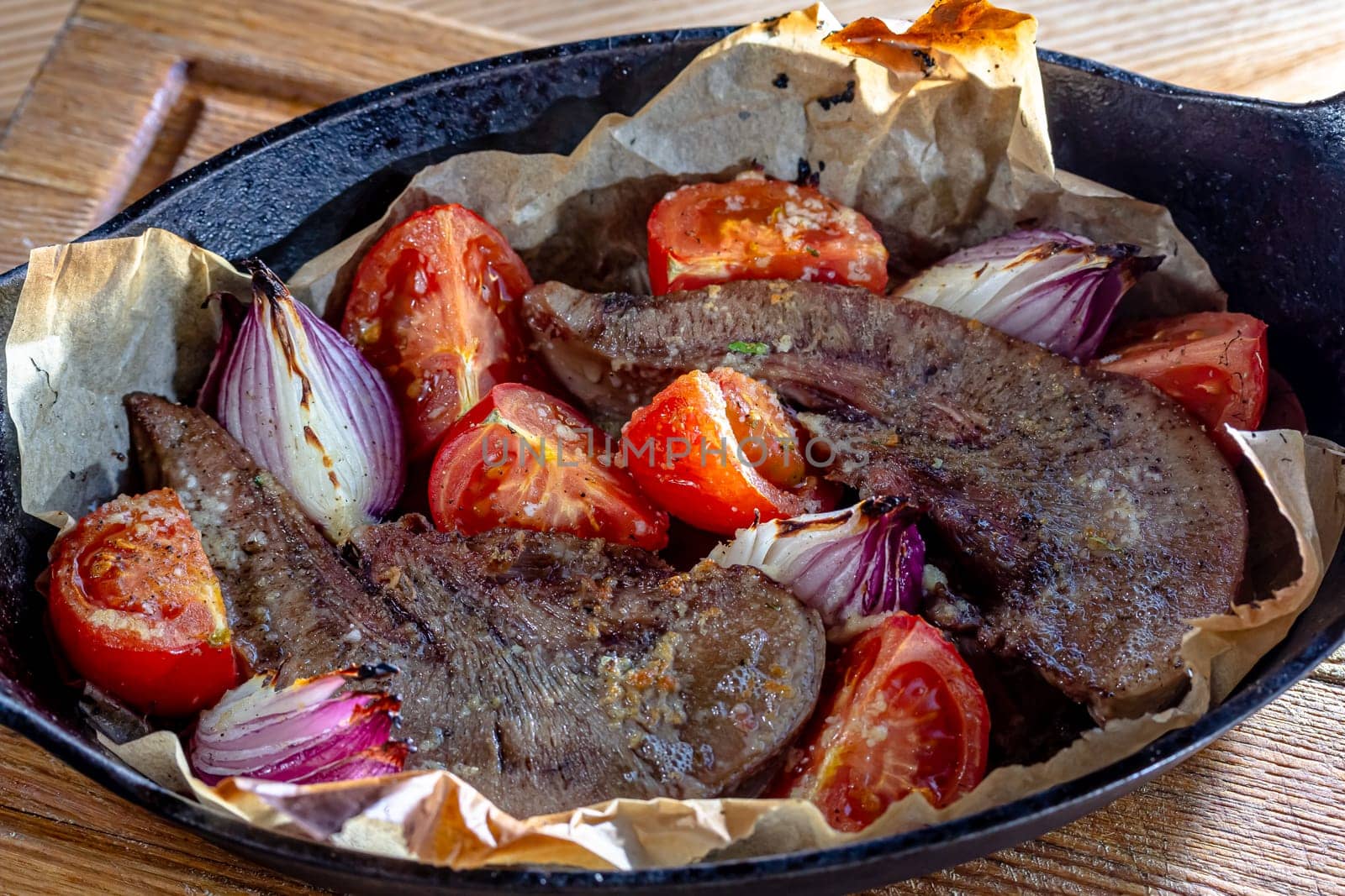 Beef tongue baked in a cast-iron pan with vegetables.