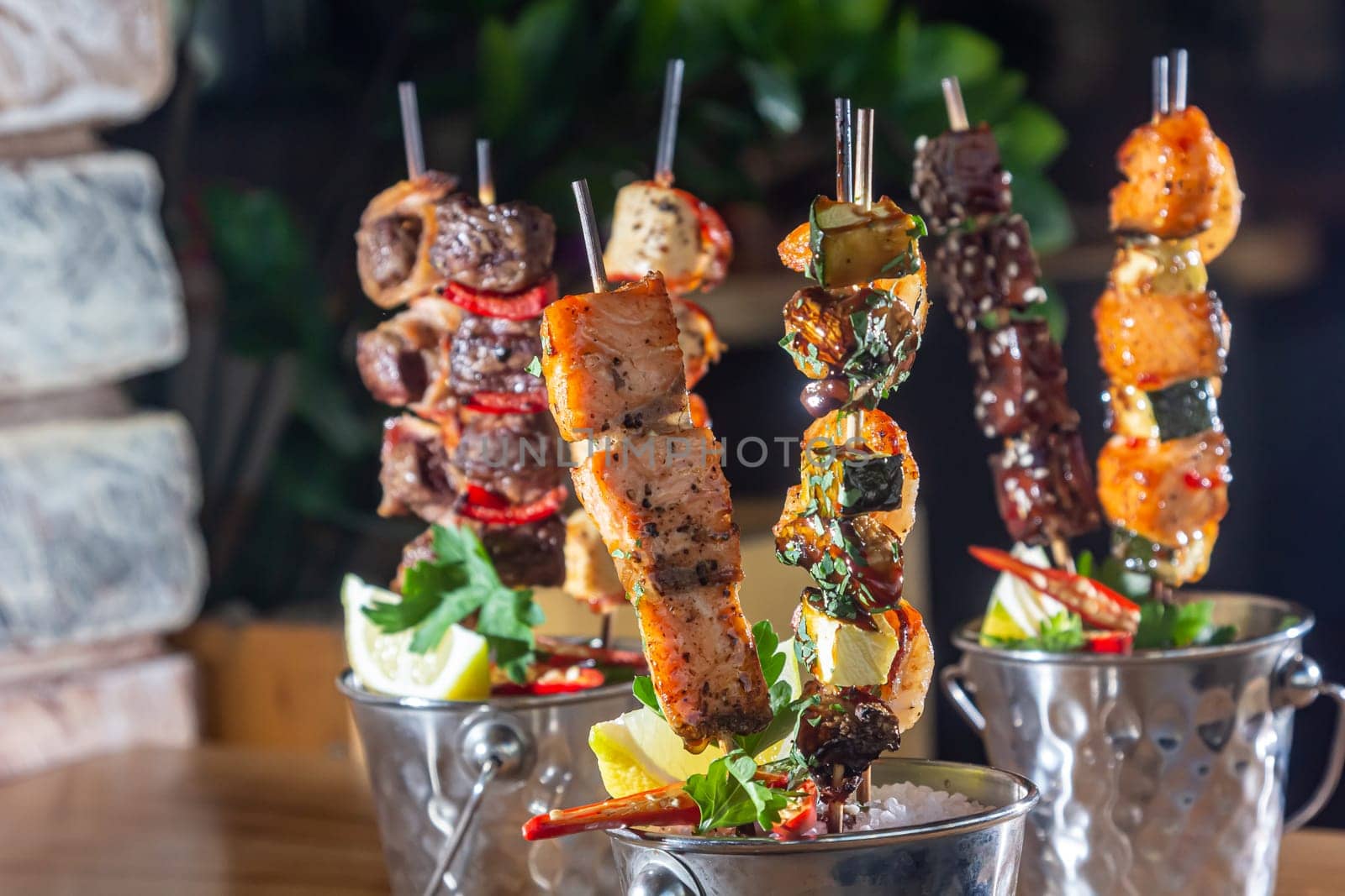 A lot of mini-kebabs of meat, fish, chicken, shrimp, vegetables on wooden skewers.