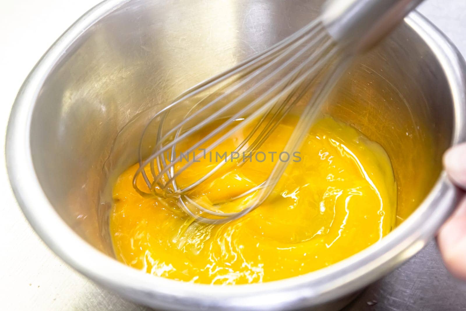 The cook whips the egg sauce with a whisk by Milanchikov