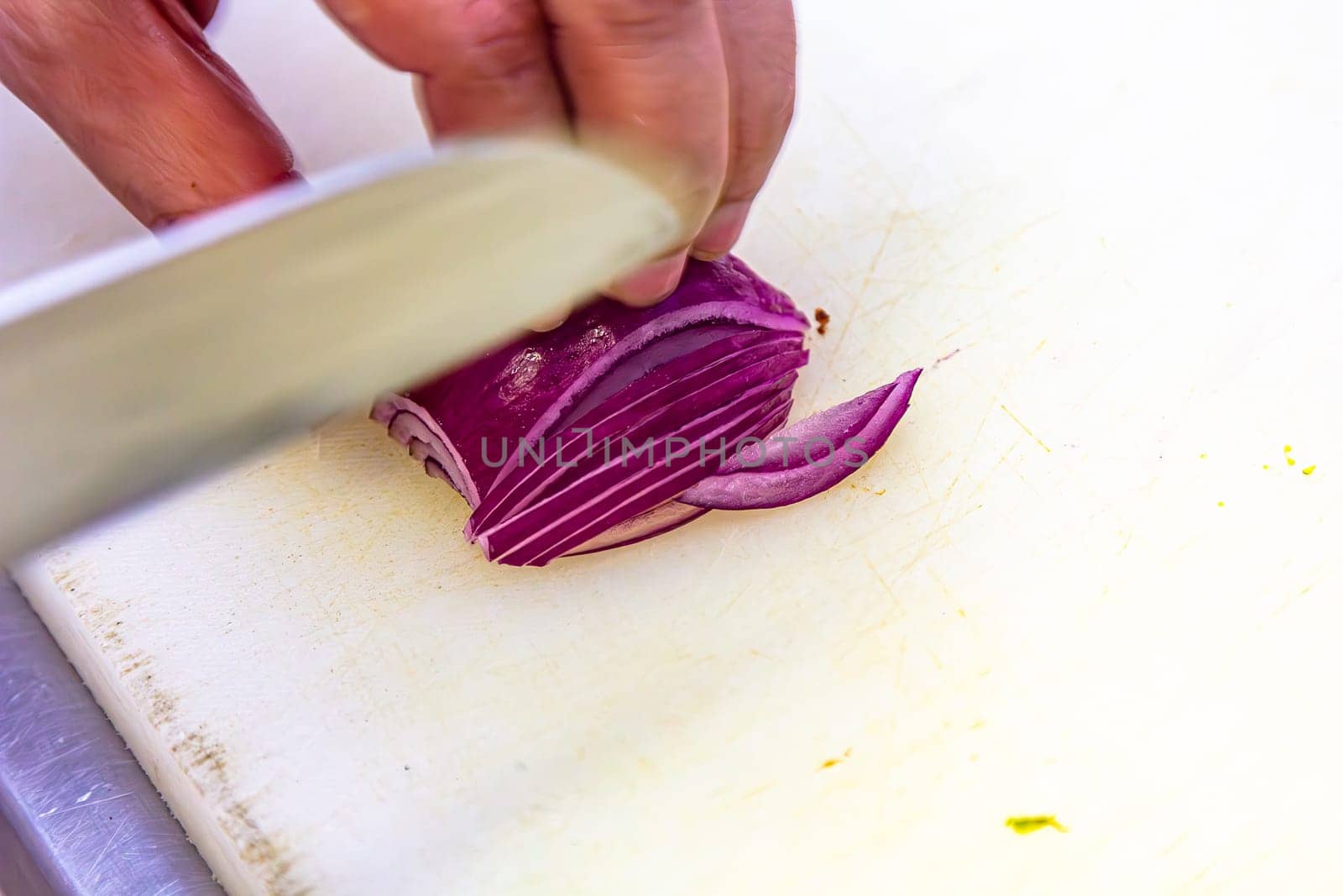 Chef chopping red onion on a cutting board