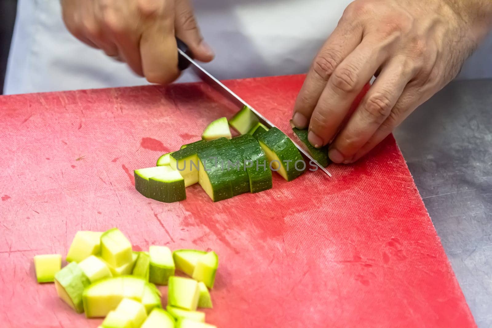 Zucchini being sliced on a red cutting board by Milanchikov