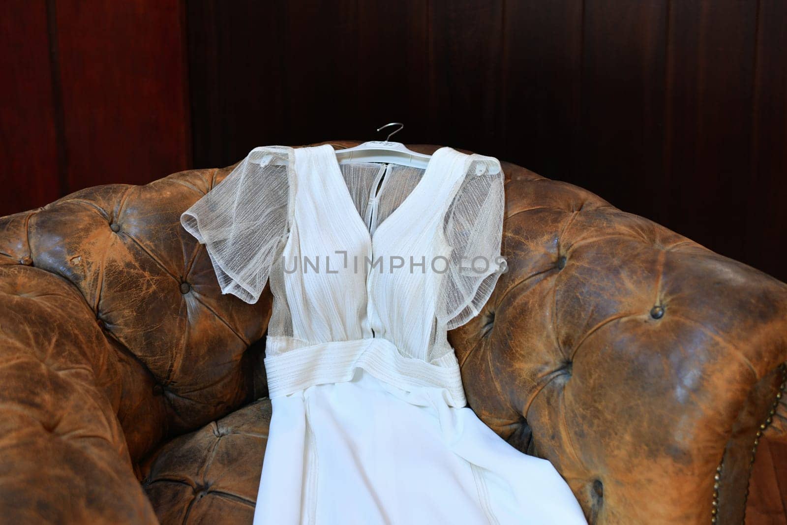Wedding dress lies on a vintage brown leather chair