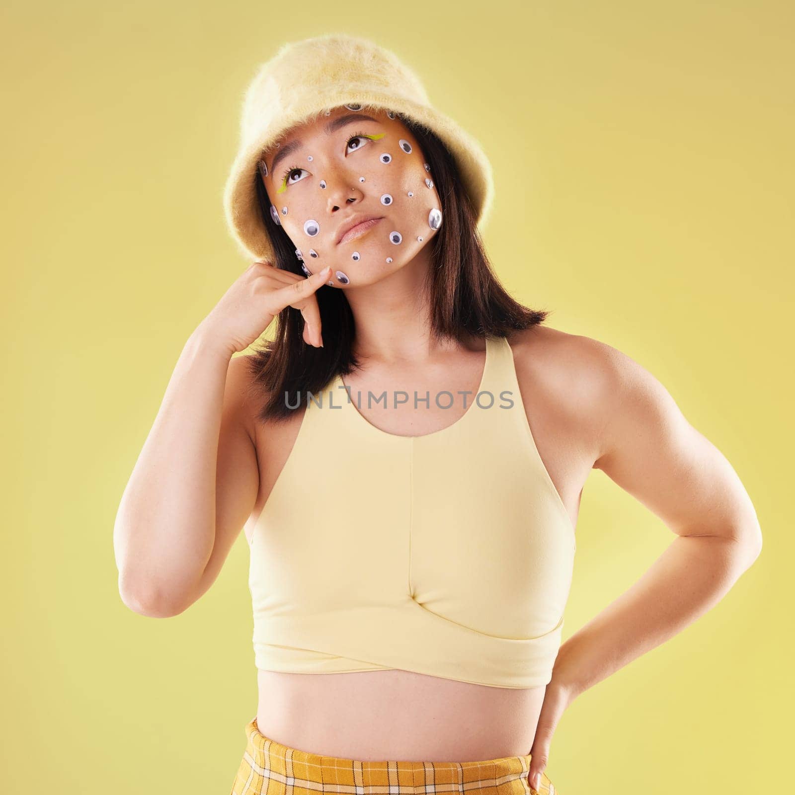 Eyes, thinking and woman with a hand call isolated on a yellow background in a studio. Idea, fashion and Asian girl with fingers in a telephone gesture for communication, conversation and talking by YuriArcurs