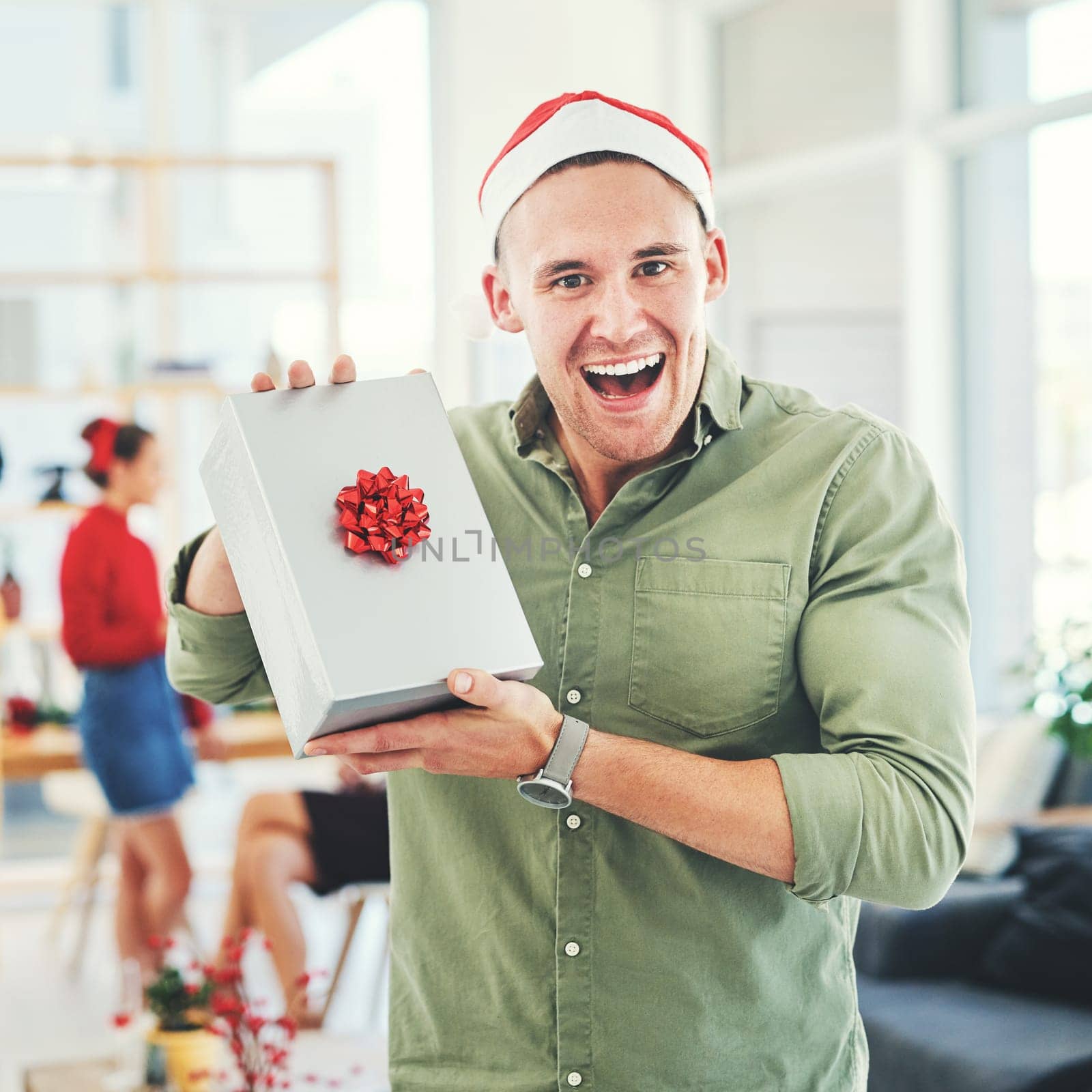 Christmas, coworking office and gift for excited and happy business man during holiday celebration with secret Santa present. Portrait of an employee holding gift box surprise at workplace event by YuriArcurs