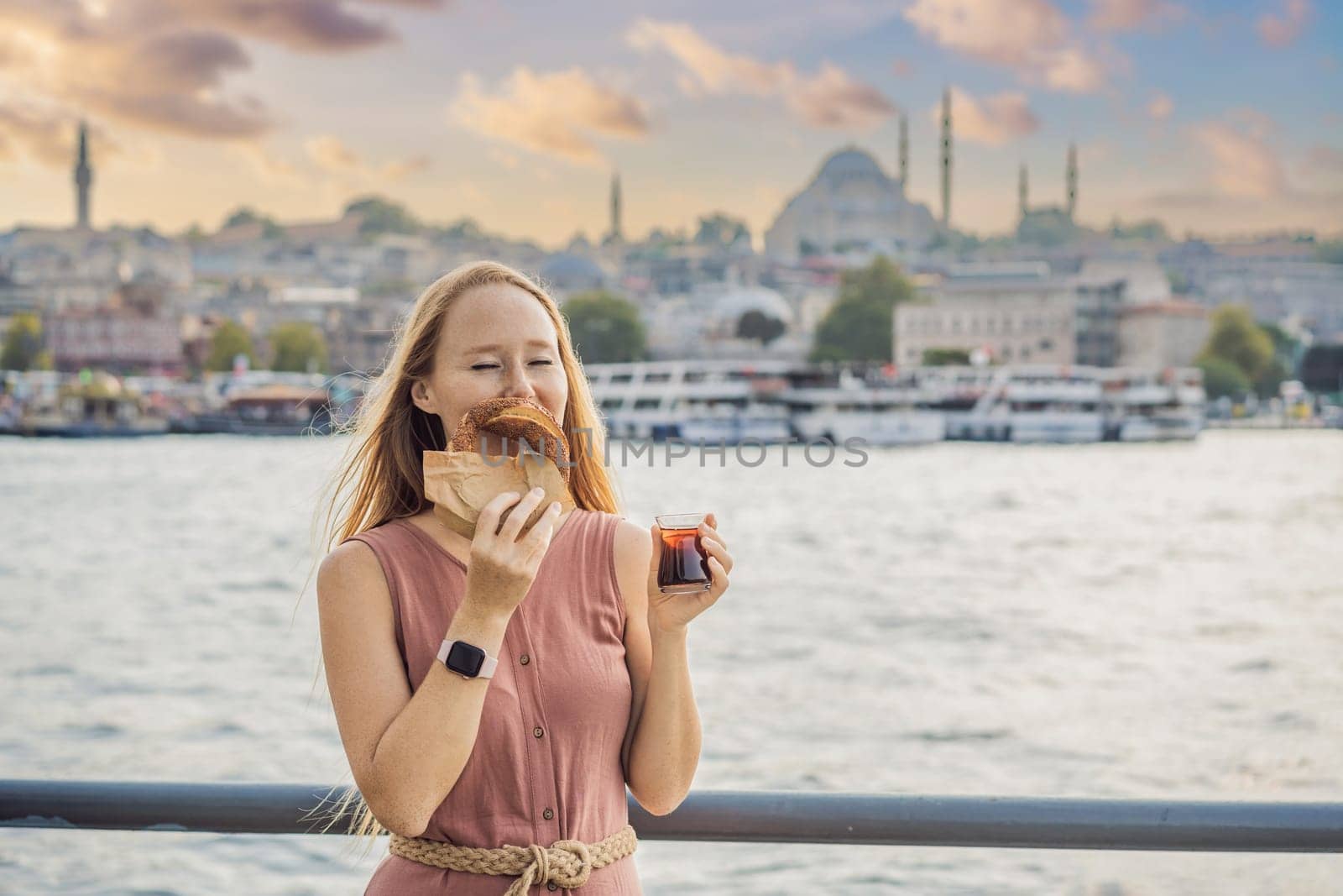 Woman in Istanbul having breakfast with Simit and a glass of Turkish tea. Glass of Turkish tea and bagel Simit against golden horn bay in Istanbul, Turkey. Turkiye.
