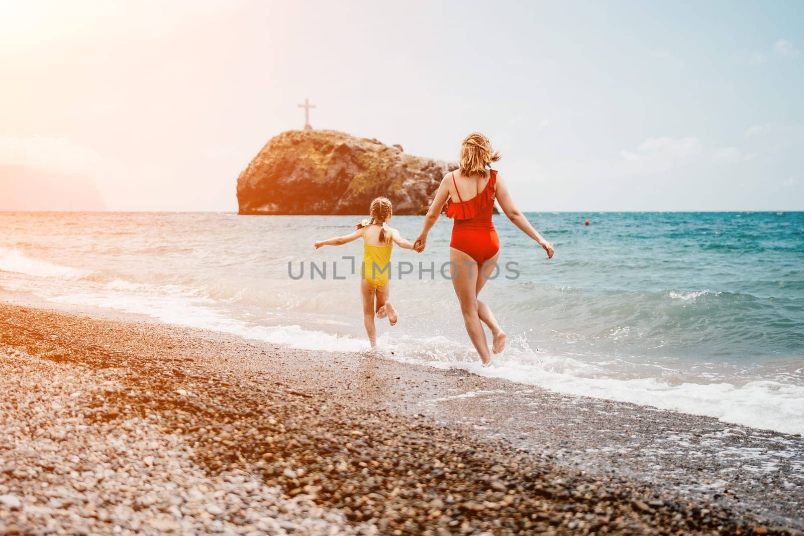 Happy loving family mother and daughter having fun together on the beach. Mum playing with her kid in holiday vacation next to the ocean - Family lifestyle and love concept by panophotograph