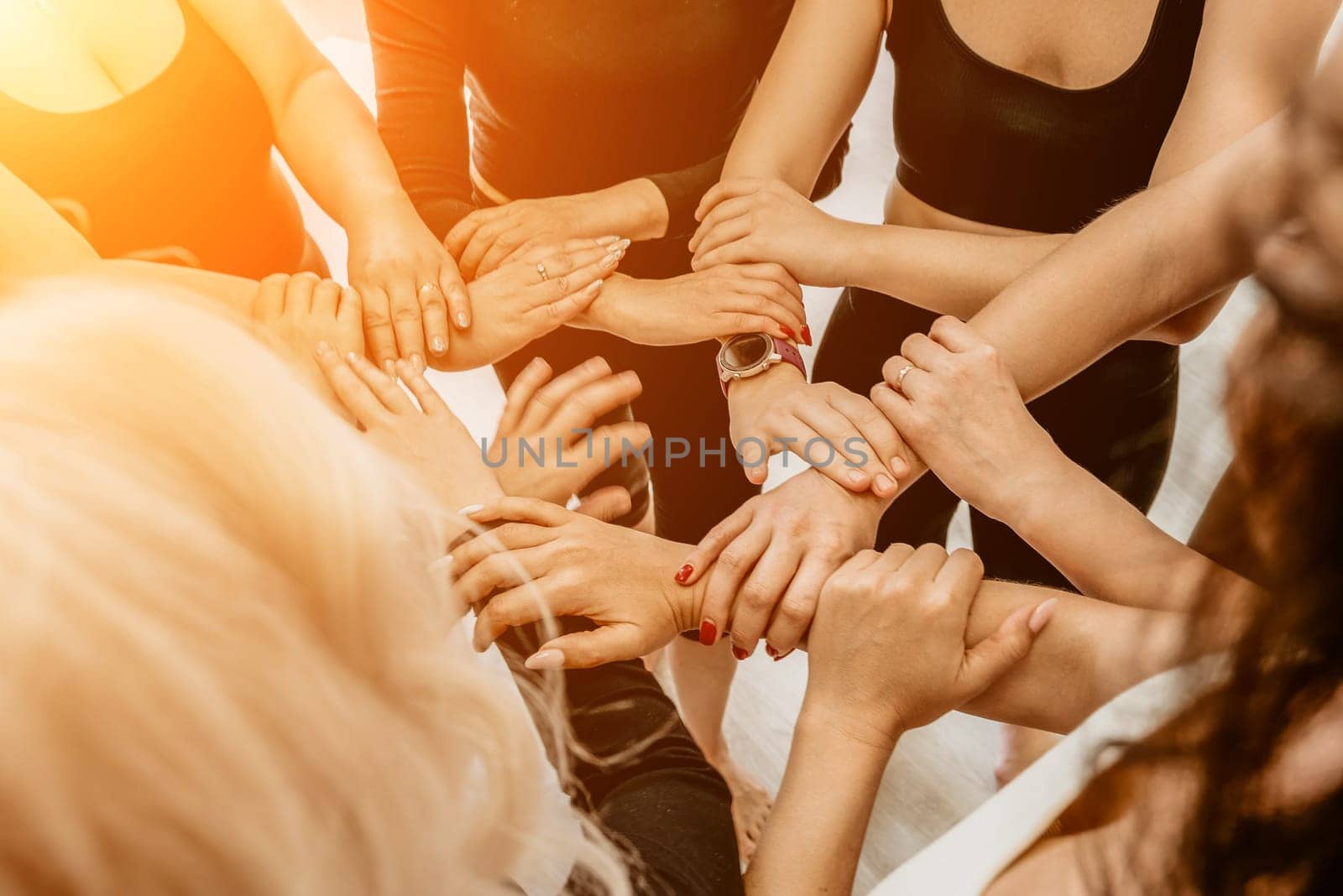 Group of young womans fitness instructor in Sportswear Leggings and Tops, stretching in the gym before pilates, on a yoga mat near the large window on a sunny day, female fitness yoga routine concept.