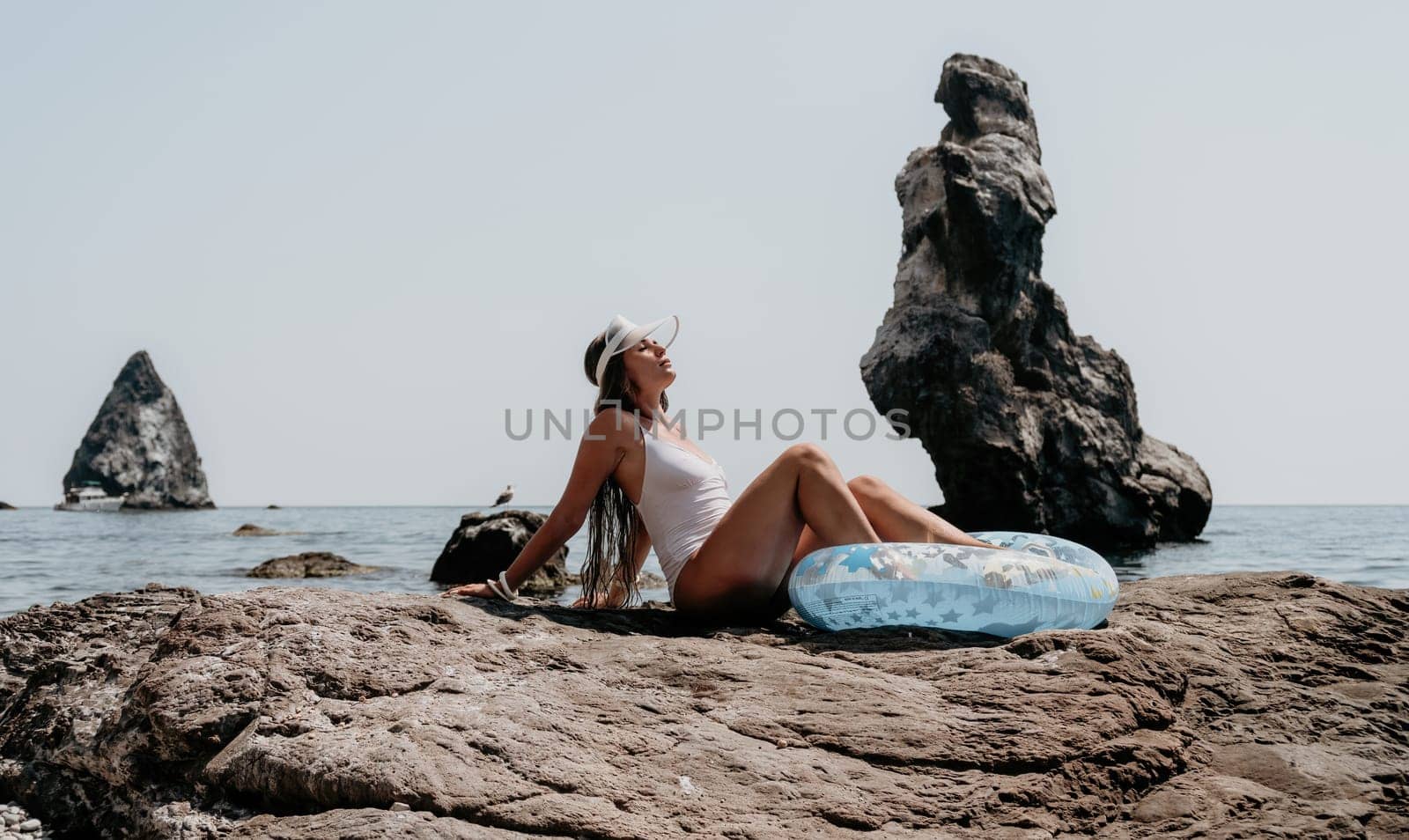 Woman summer sea. Happy woman swimming with inflatable donut on the beach in summer sunny day, surrounded by volcanic mountains. Summer vacation concept