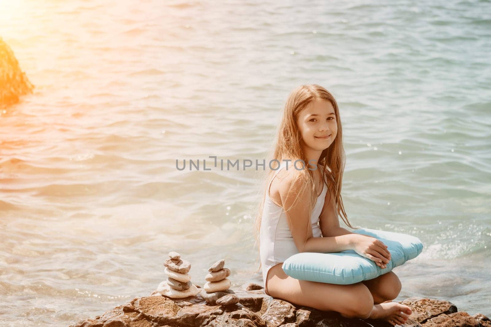 Woman with daughter bilds stones pyramid on seashore on a sunny day on the blue sea background. Happy family holidays. Pebble beach, calm sea. Concept of happy vacation on the sea, meditation, spa by panophotograph