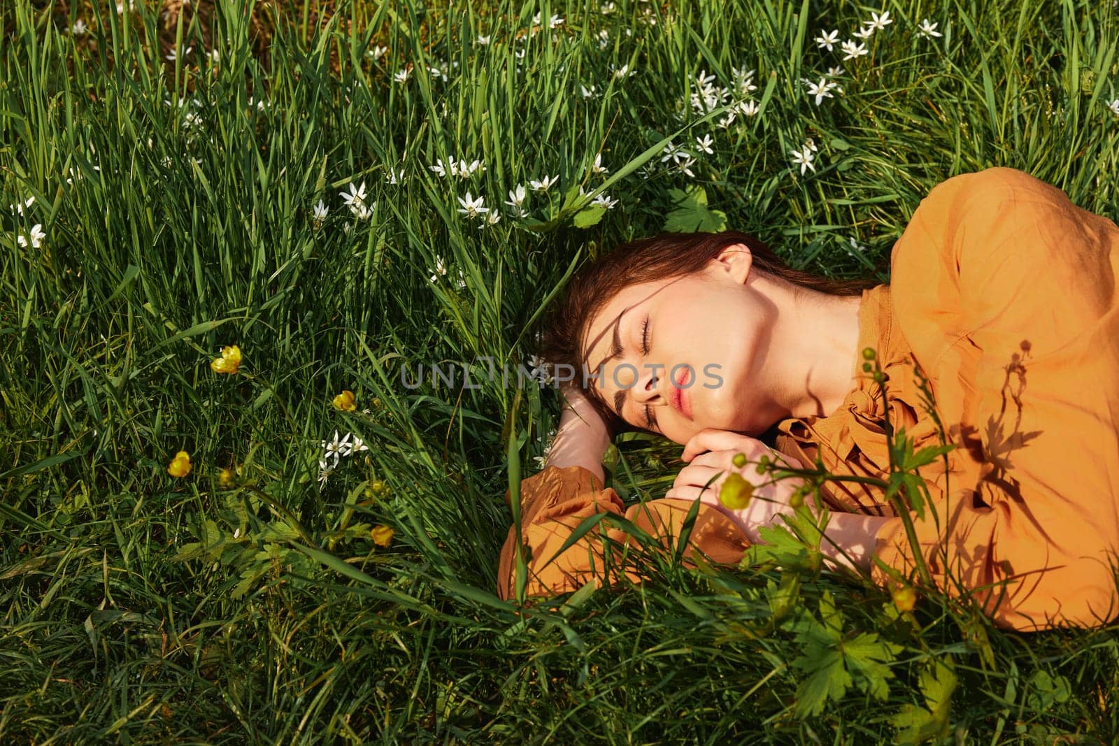 a close horizontal photo of a happy woman lying in the grass with her eyes closed and a pleasant smile on her face. High quality photo