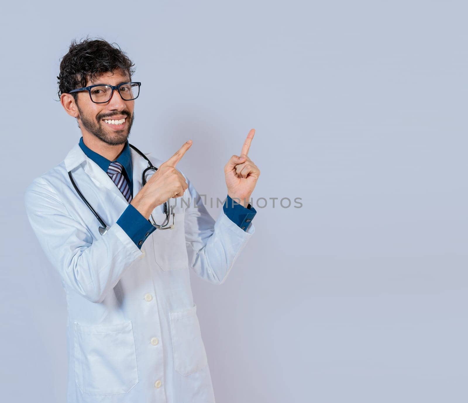 Bearded doctor pointing a promotion with finger isolated. Happy bearded doctor pointing at advertising space isolated