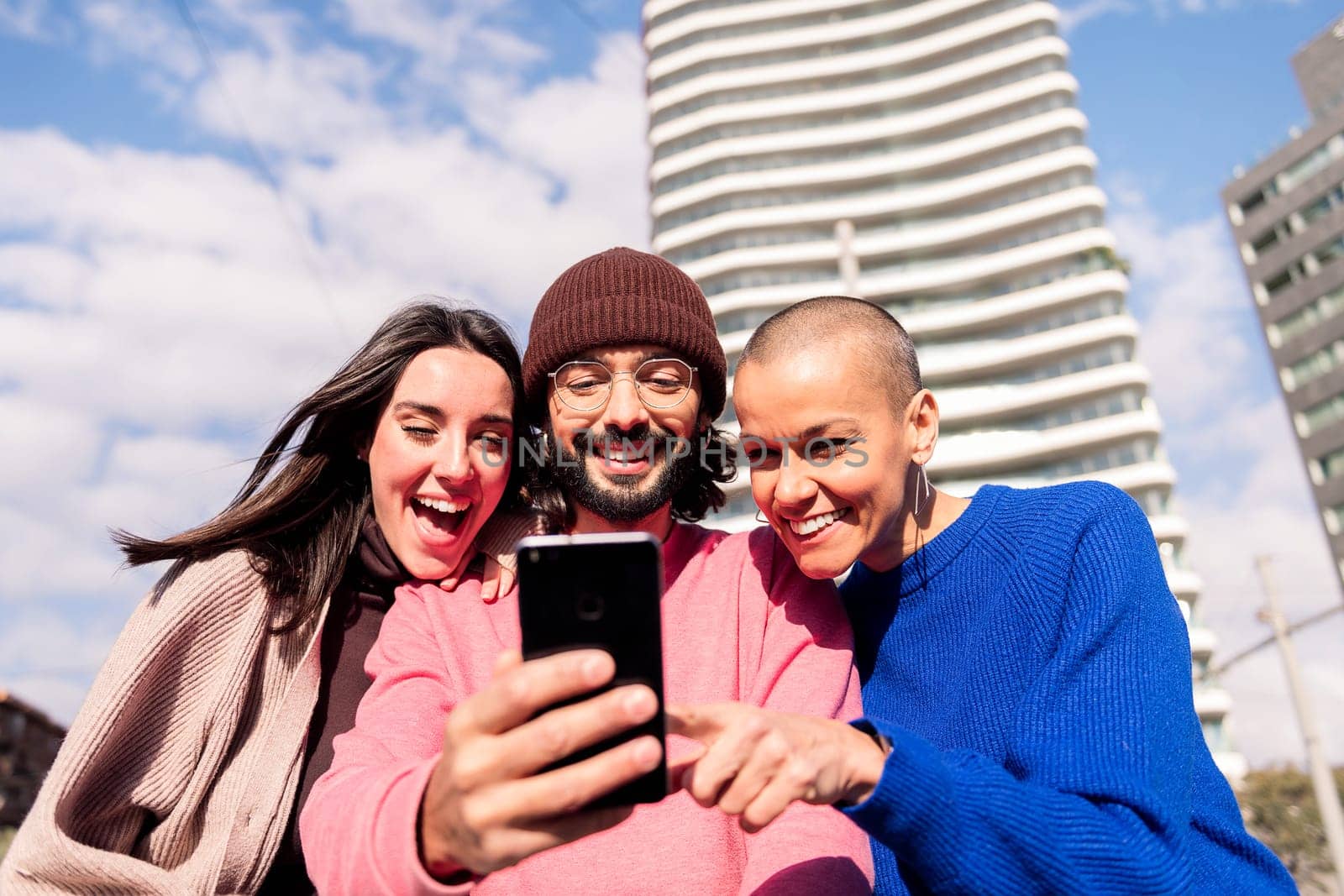 three young friends enjoying together with a phone at city, concept of fun with technology and urban lifestyle, copy space for text