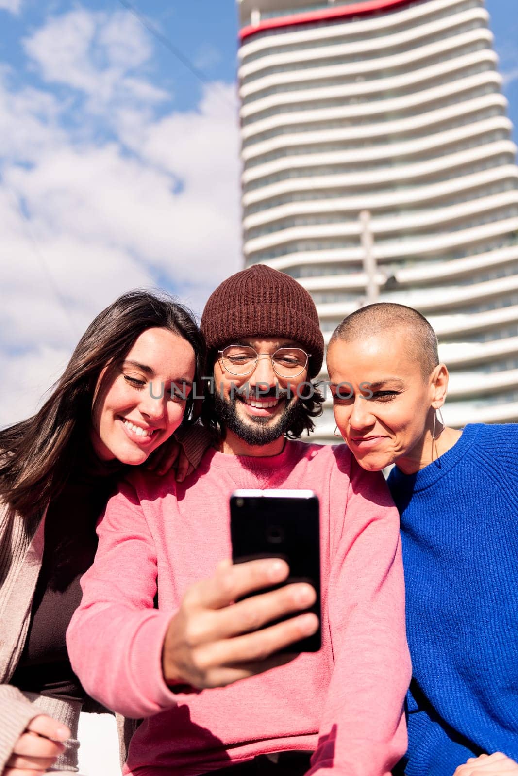 three young friends enjoying together with a phone at city, concept of fun with technology and urban lifestyle, copy space for text