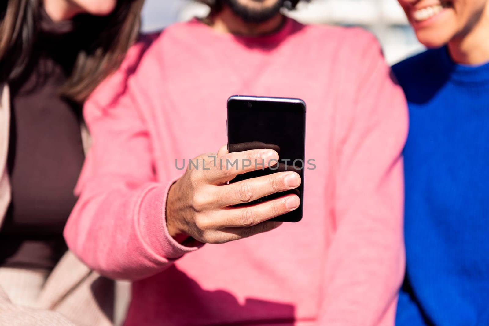 close up of the hand of a man holding a mobile phone sharing a moment with unrecognizable friends, concept of technology of communication and connectivity in a digital world