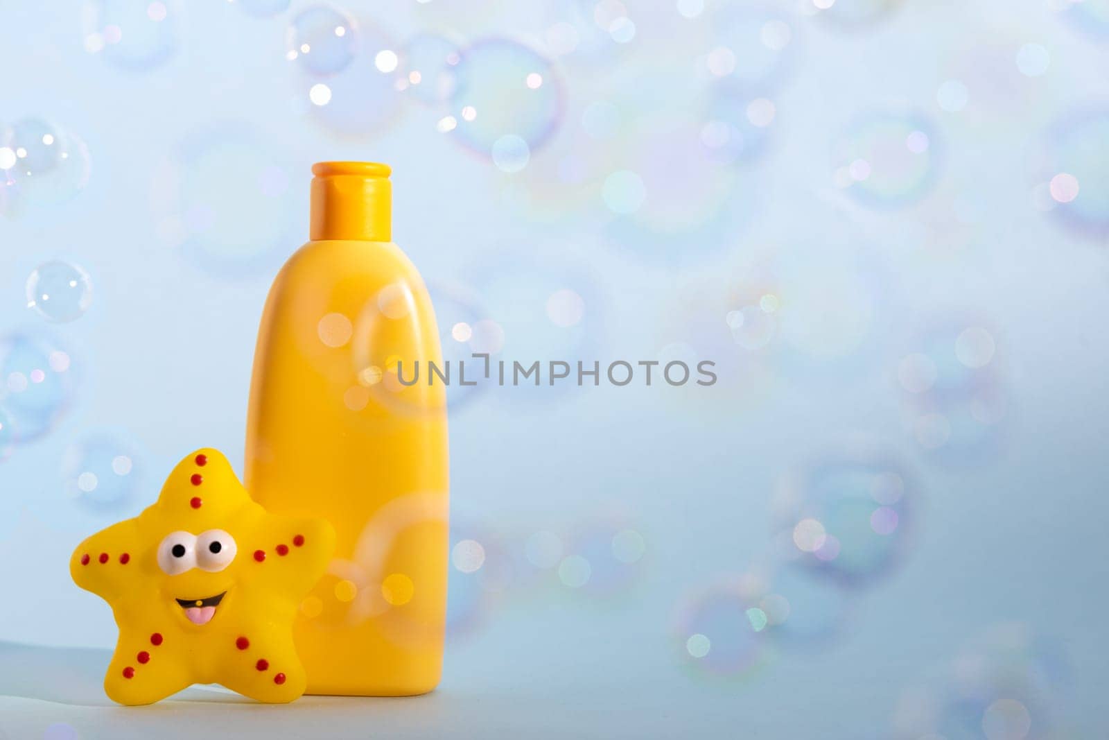 Baby bath foam or liquid soap with yellow star fish and many flying soap bubbles. Children's bath time concept. Copy space