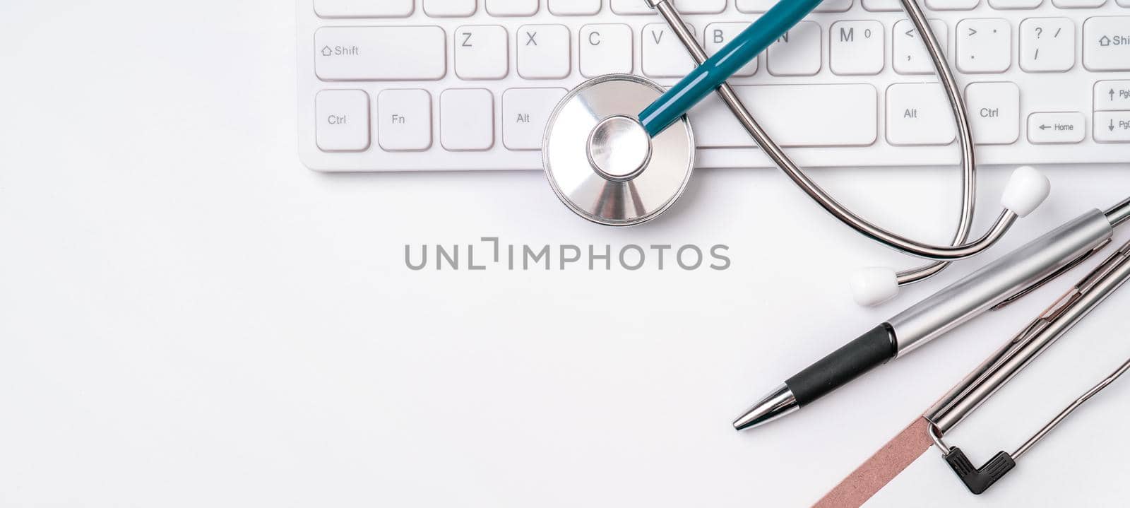 Stethoscope on keyboard on white table background. Online medical information treatment technology office concept, top view, flat lay, copy space by ROMIXIMAGE