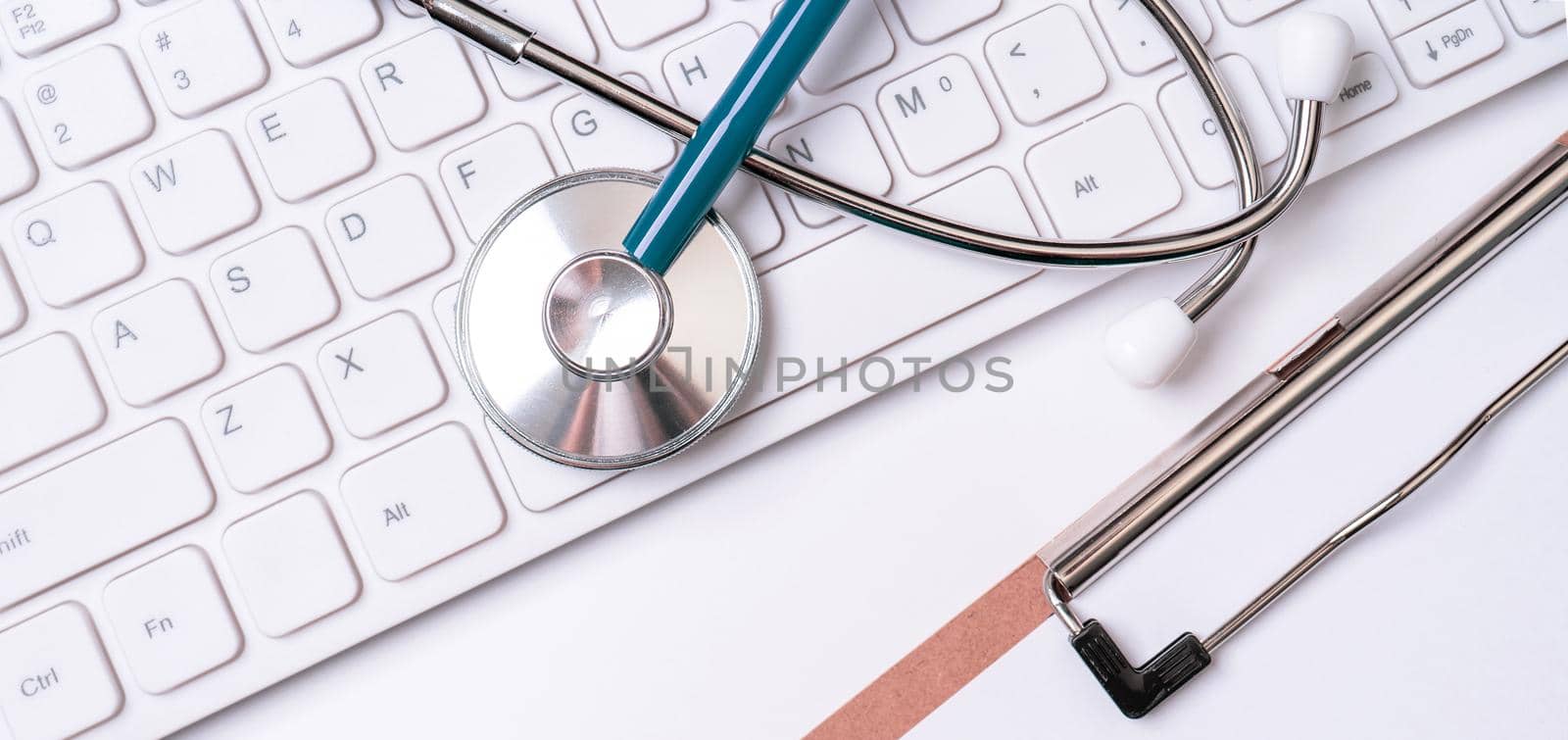 Stethoscope on keyboard on white table background. Online medical information treatment technology office concept, top view, flat lay, copy space by ROMIXIMAGE